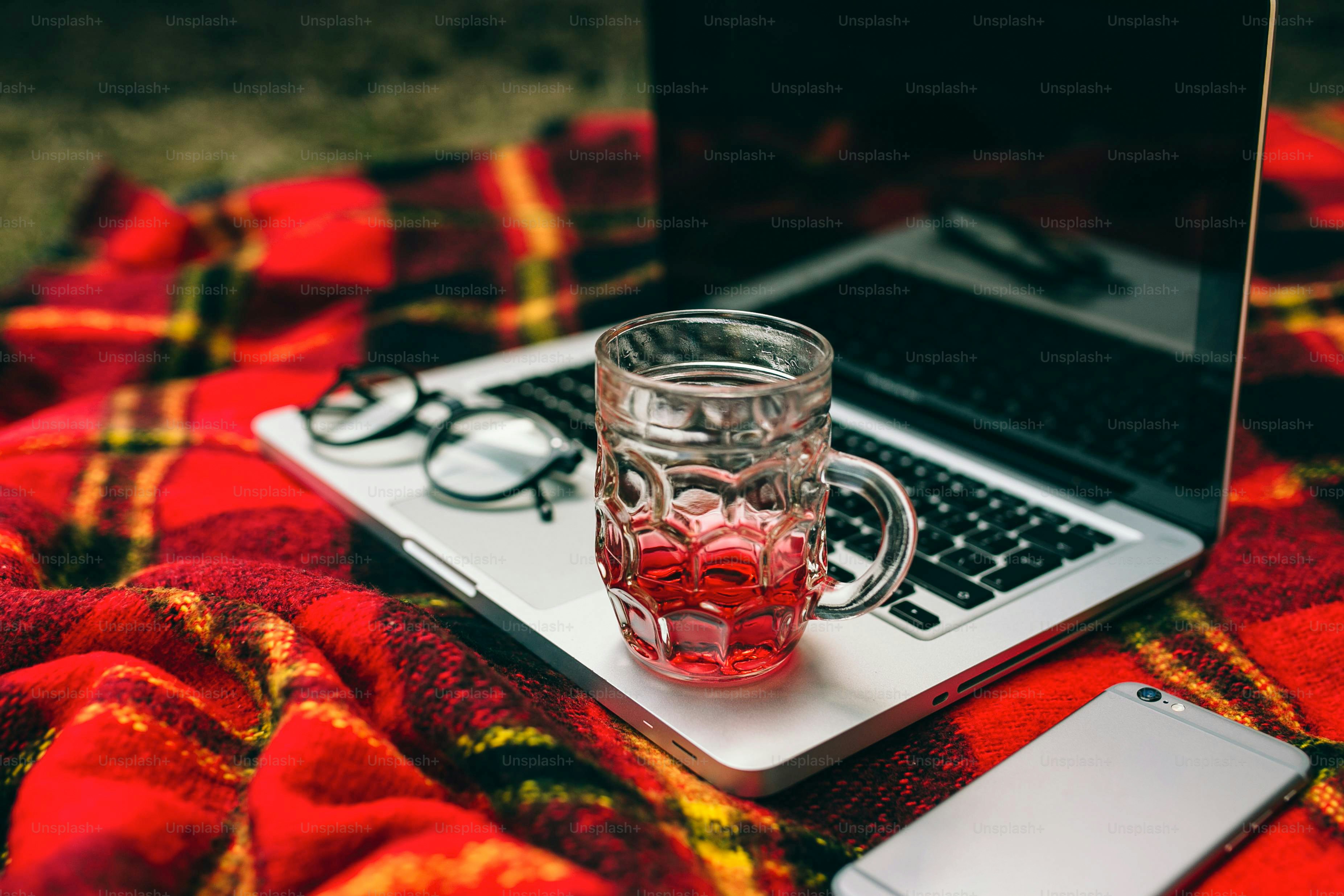 Laptop, drink, and glasses on a red blanket