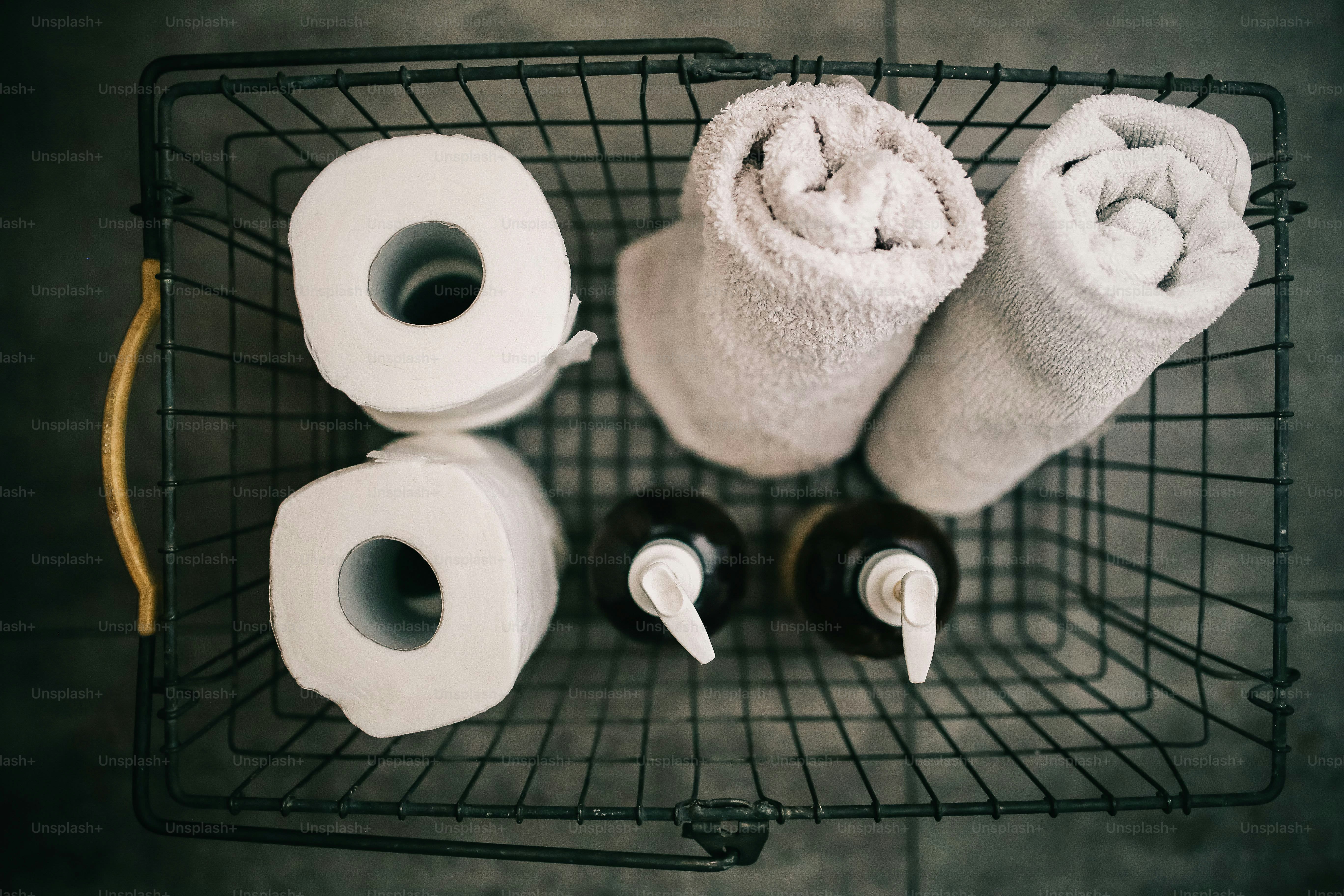 Two rolls of toilet paper and two towels in basket.