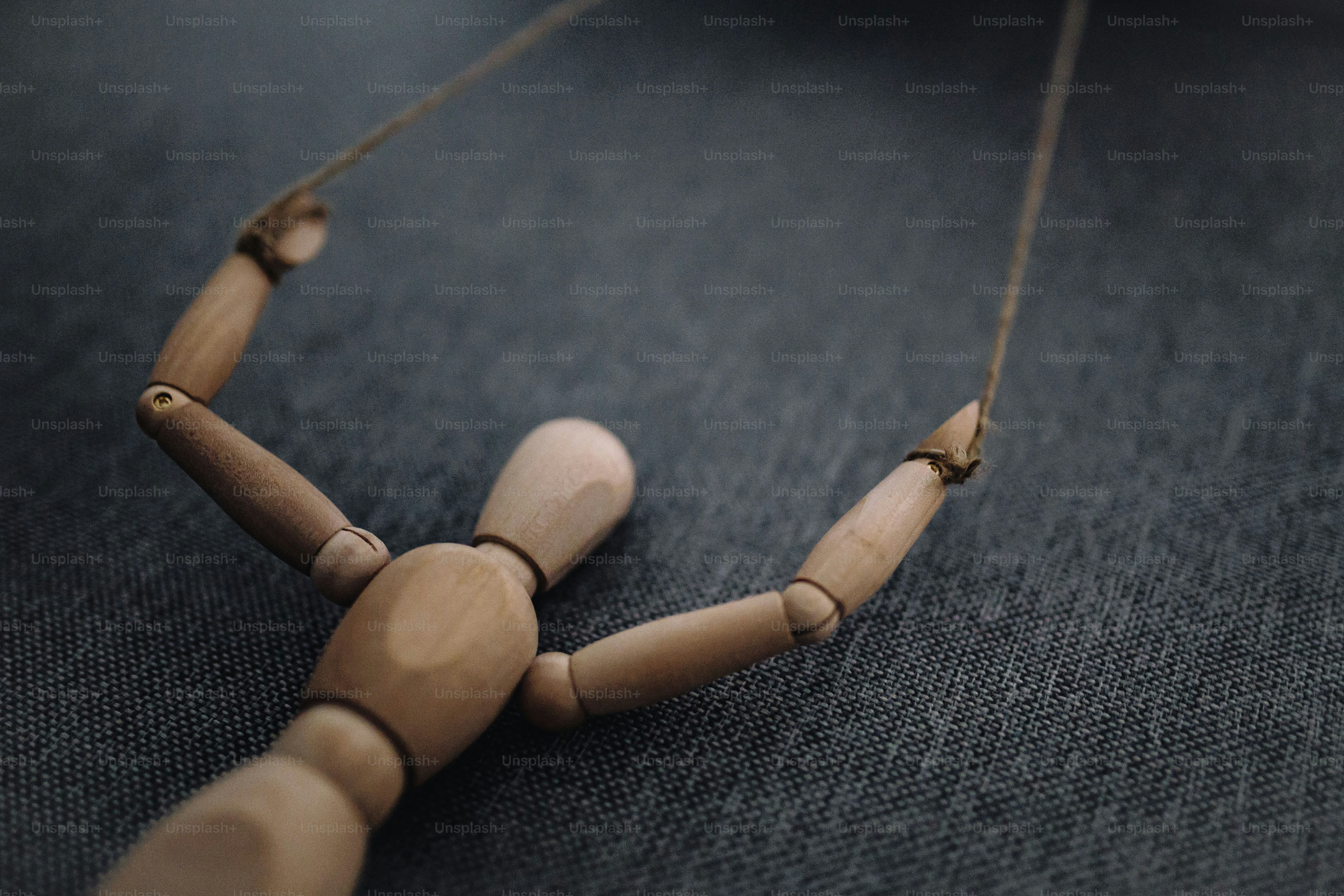 Muñeca marioneta de madera con cuerdas sobre fondo oscuro