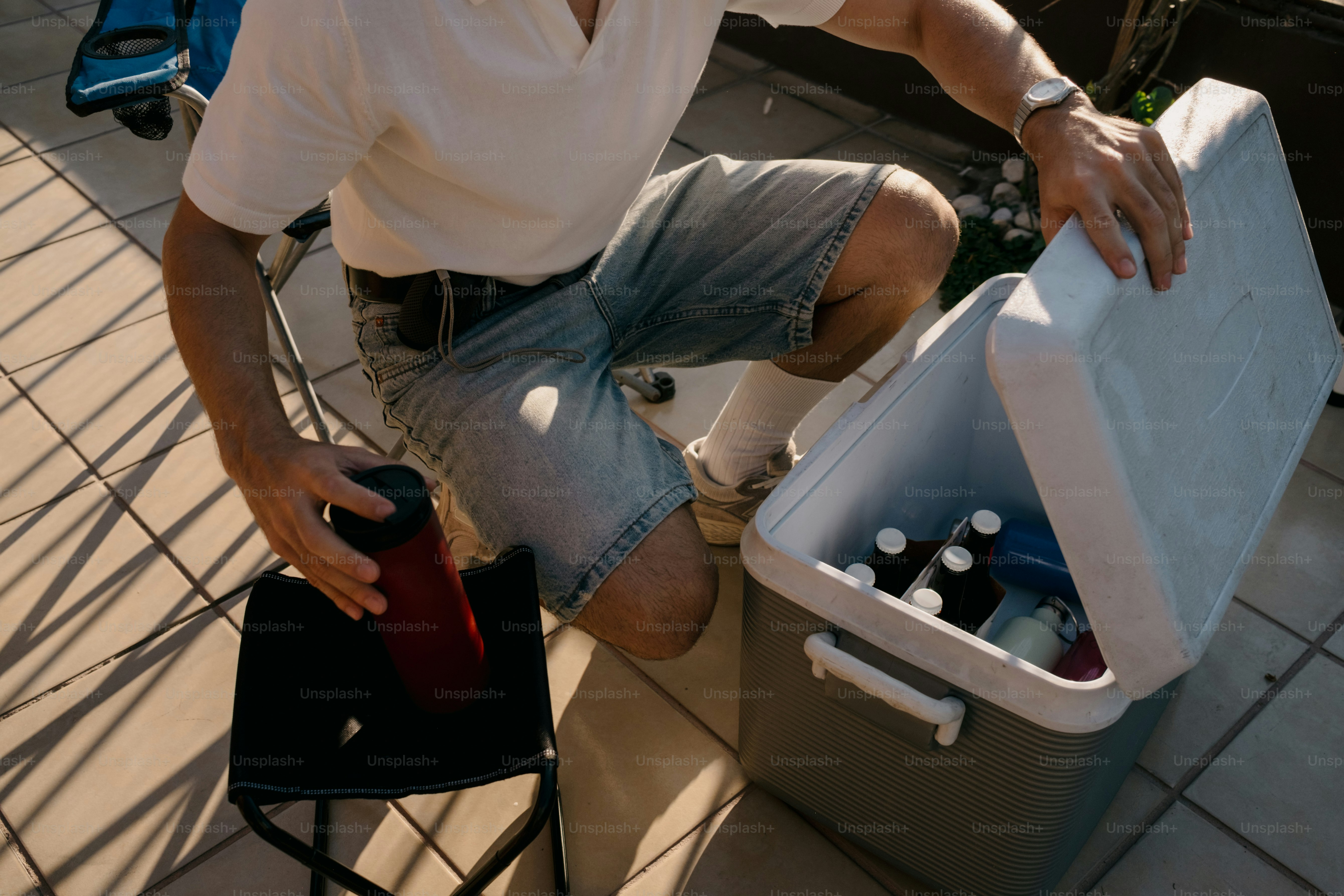 Man placing red thermos into cooler with bottles