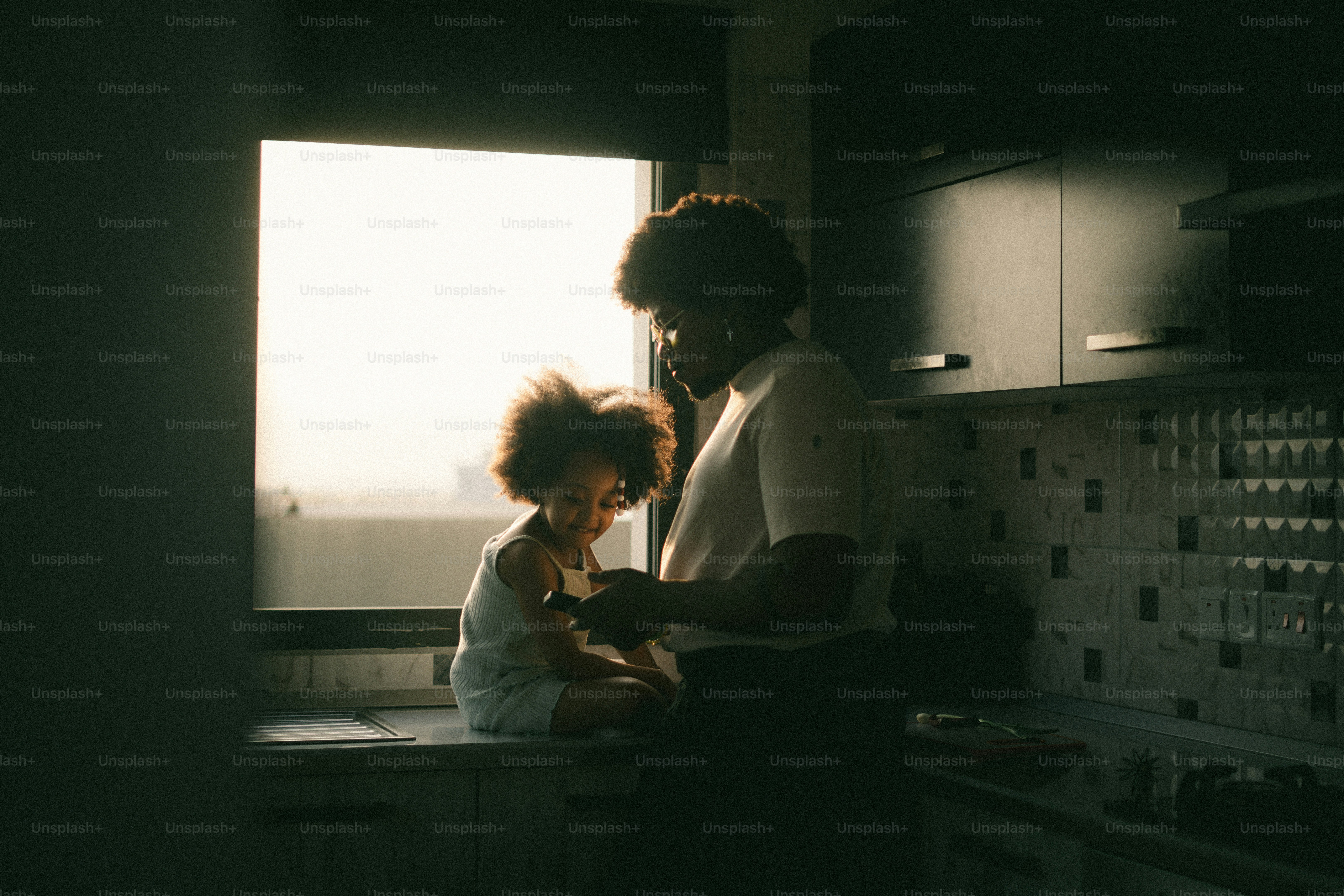 Ibu dan anak di dekat jendela yang diterangi sinar matahari di dapur.