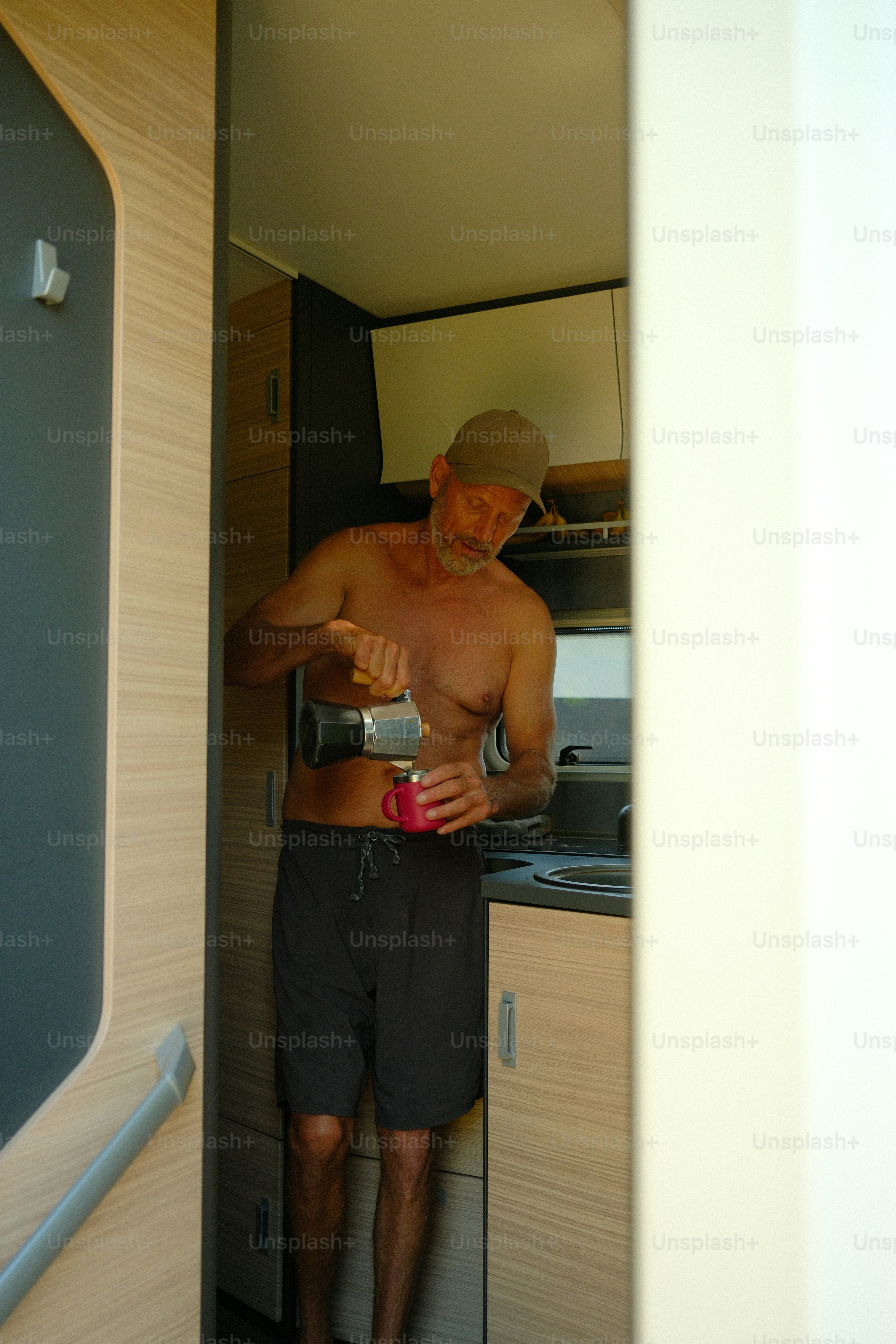 Pria menuangkan kopi ke dalam cangkir di dalam camper van.