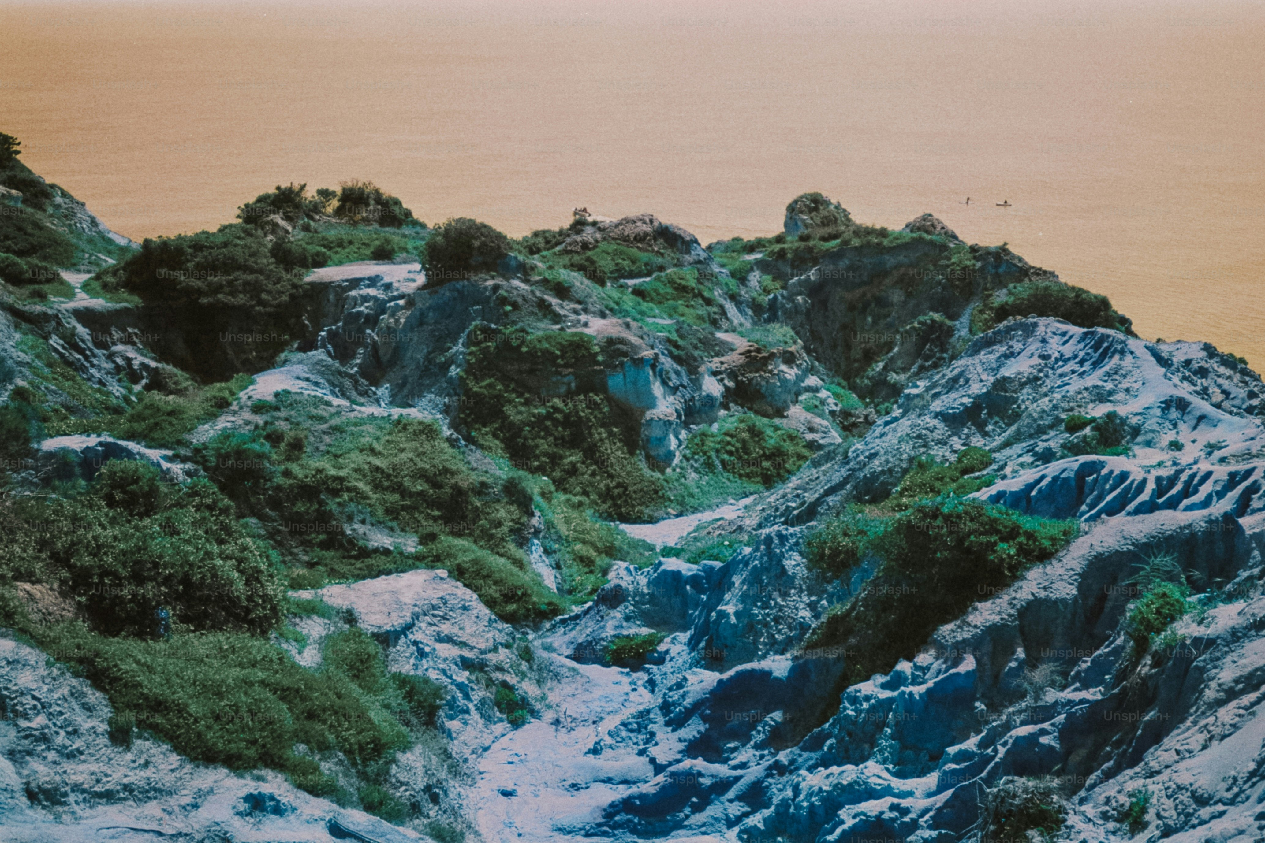Green and blue rocky terrain with distant water