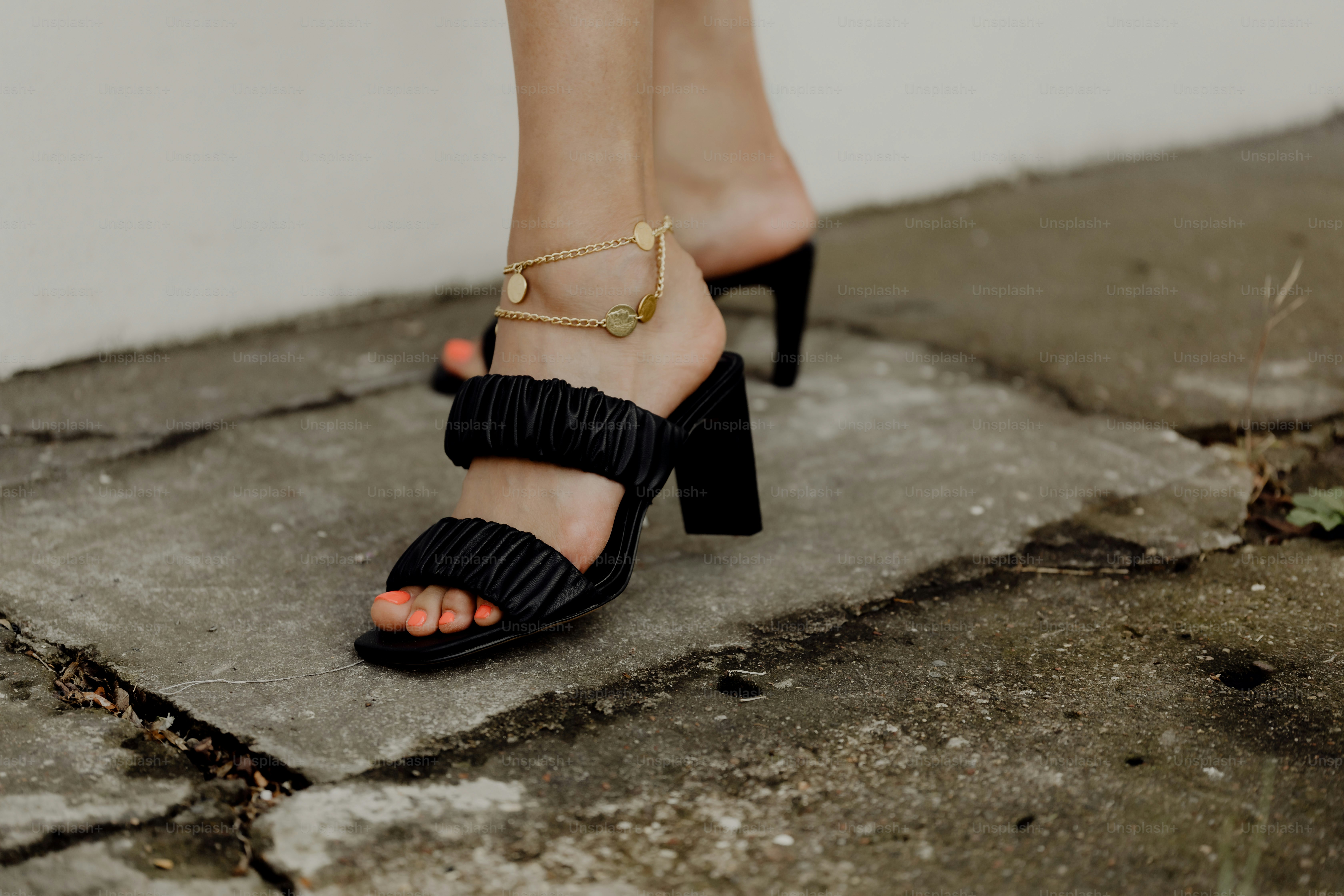 Una persona vestida con sandalias negras de tacón fruncido