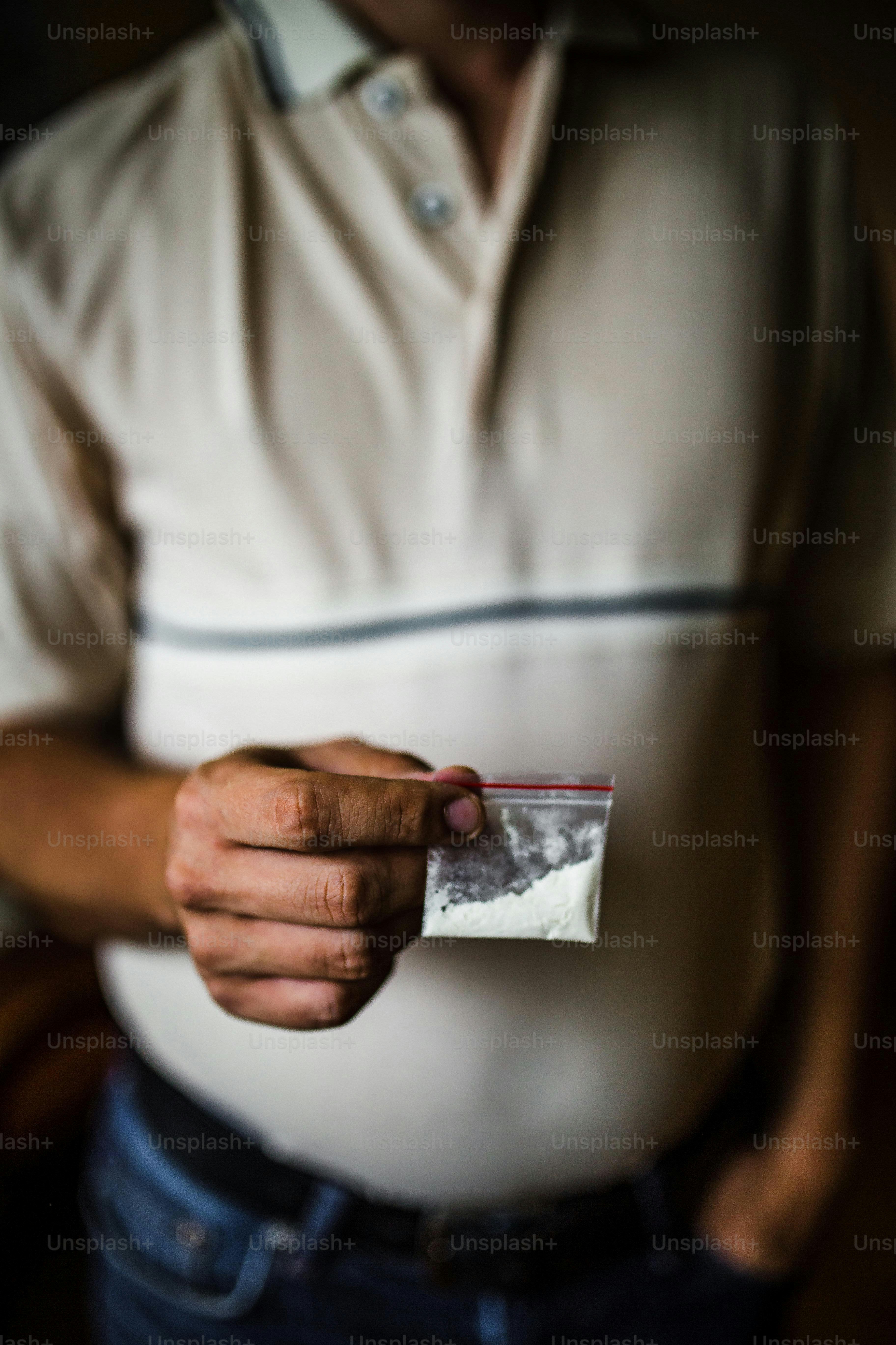 Man holding a small bag of white powder.