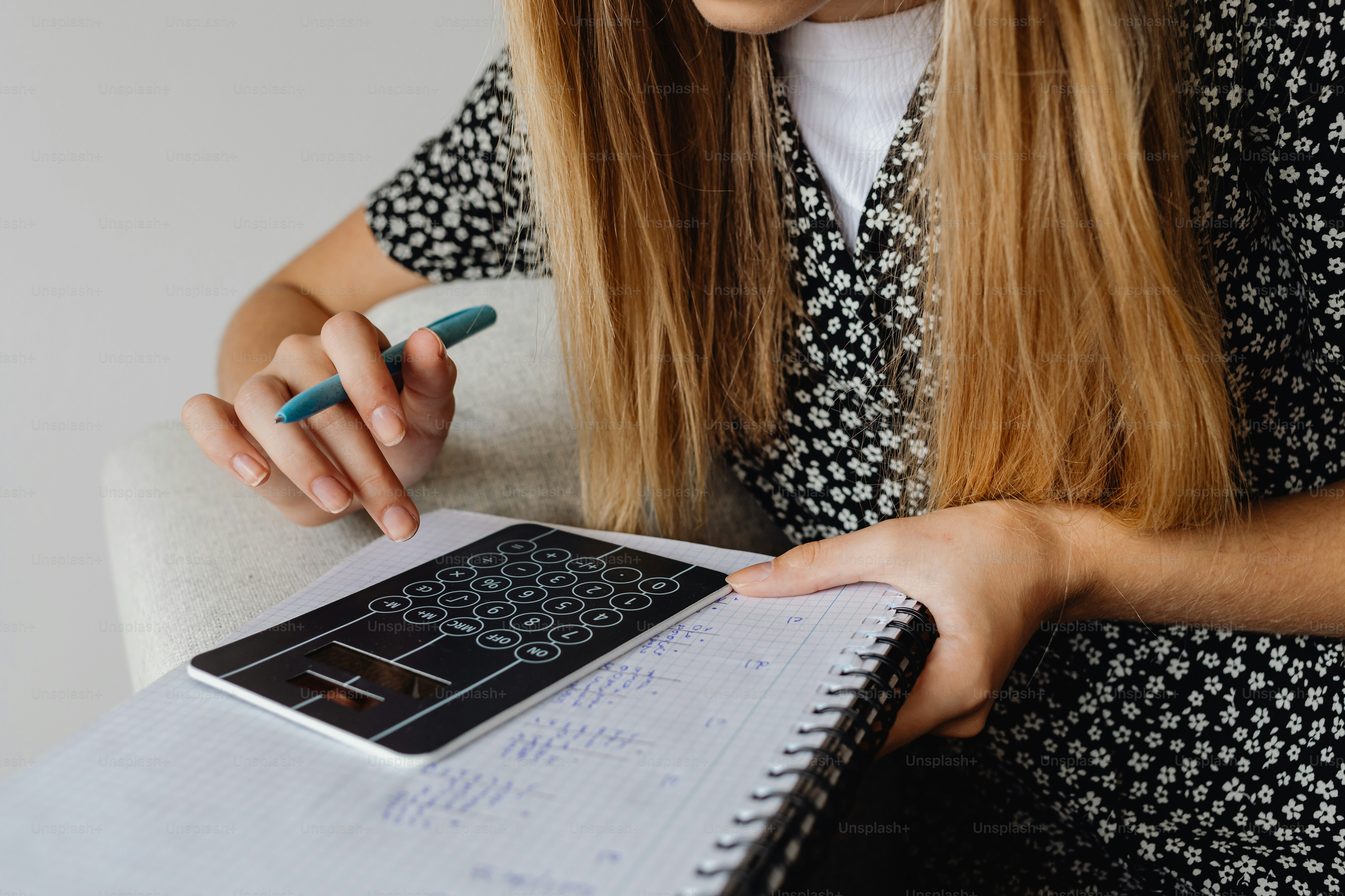Woman writing in notebook with pen and tablet.