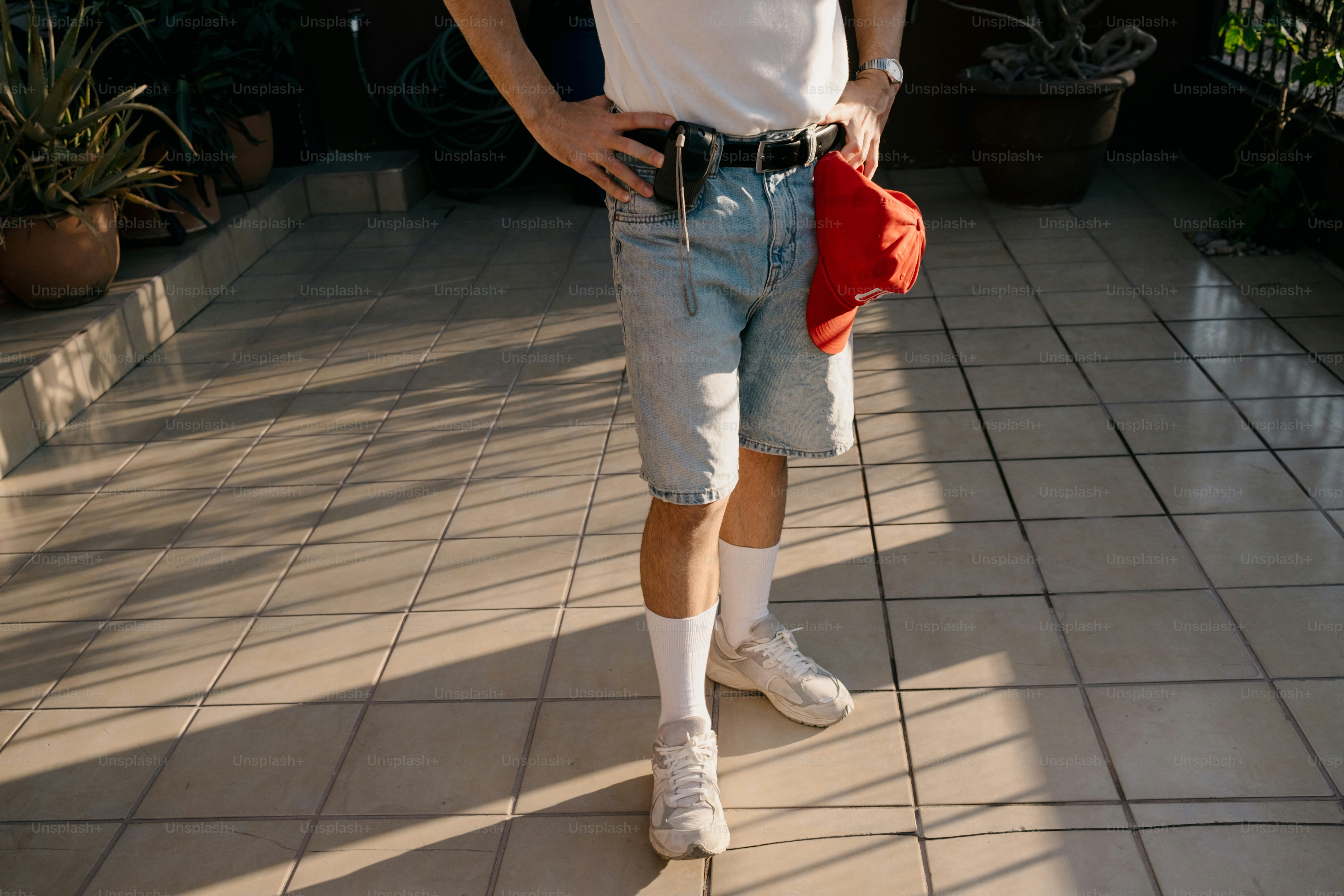 Orang yang mengenakan celana pendek denim dan sepatu kets putih di lantai keramik.