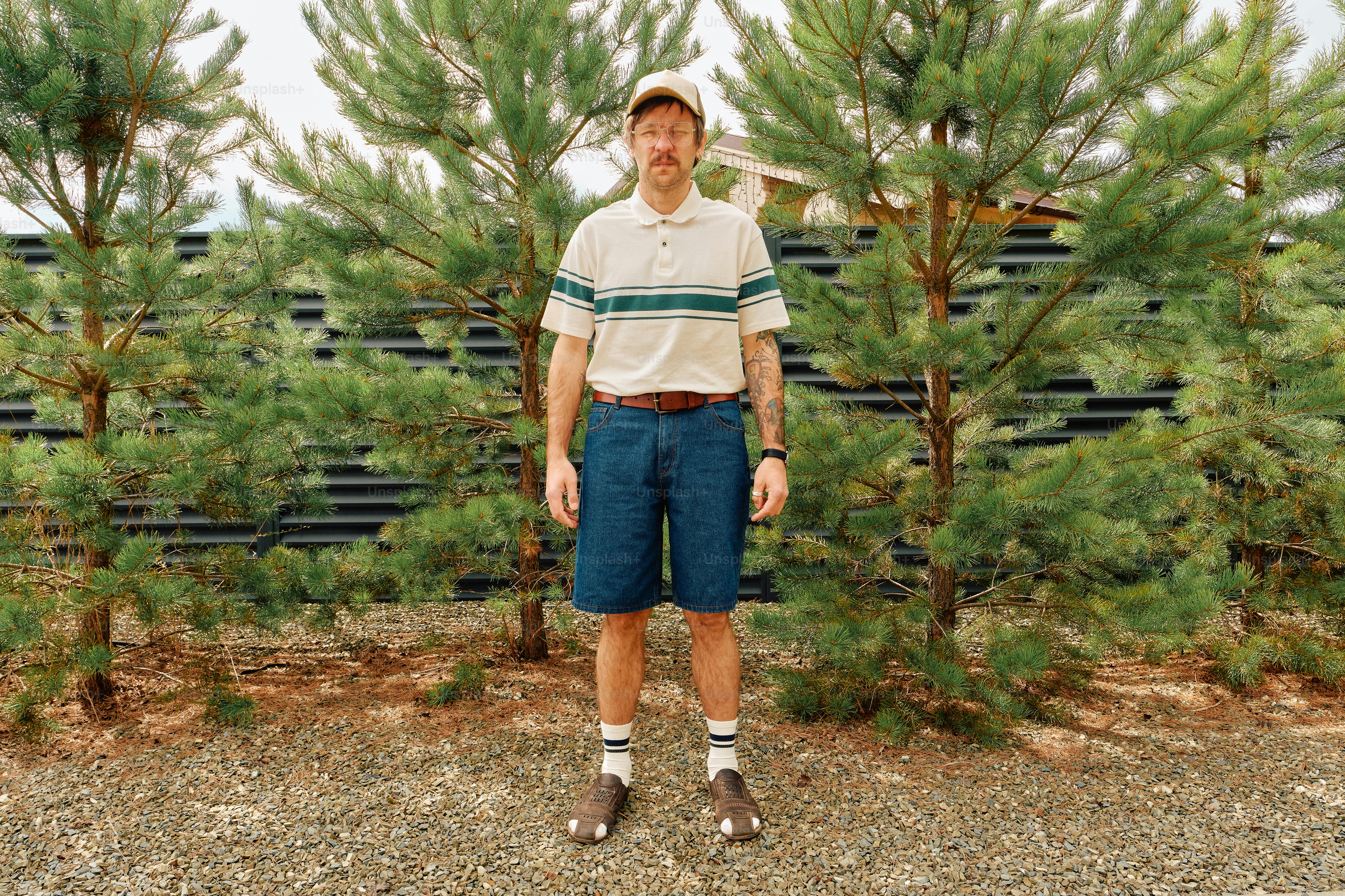 Man in polo shirt and denim shorts standing outdoors