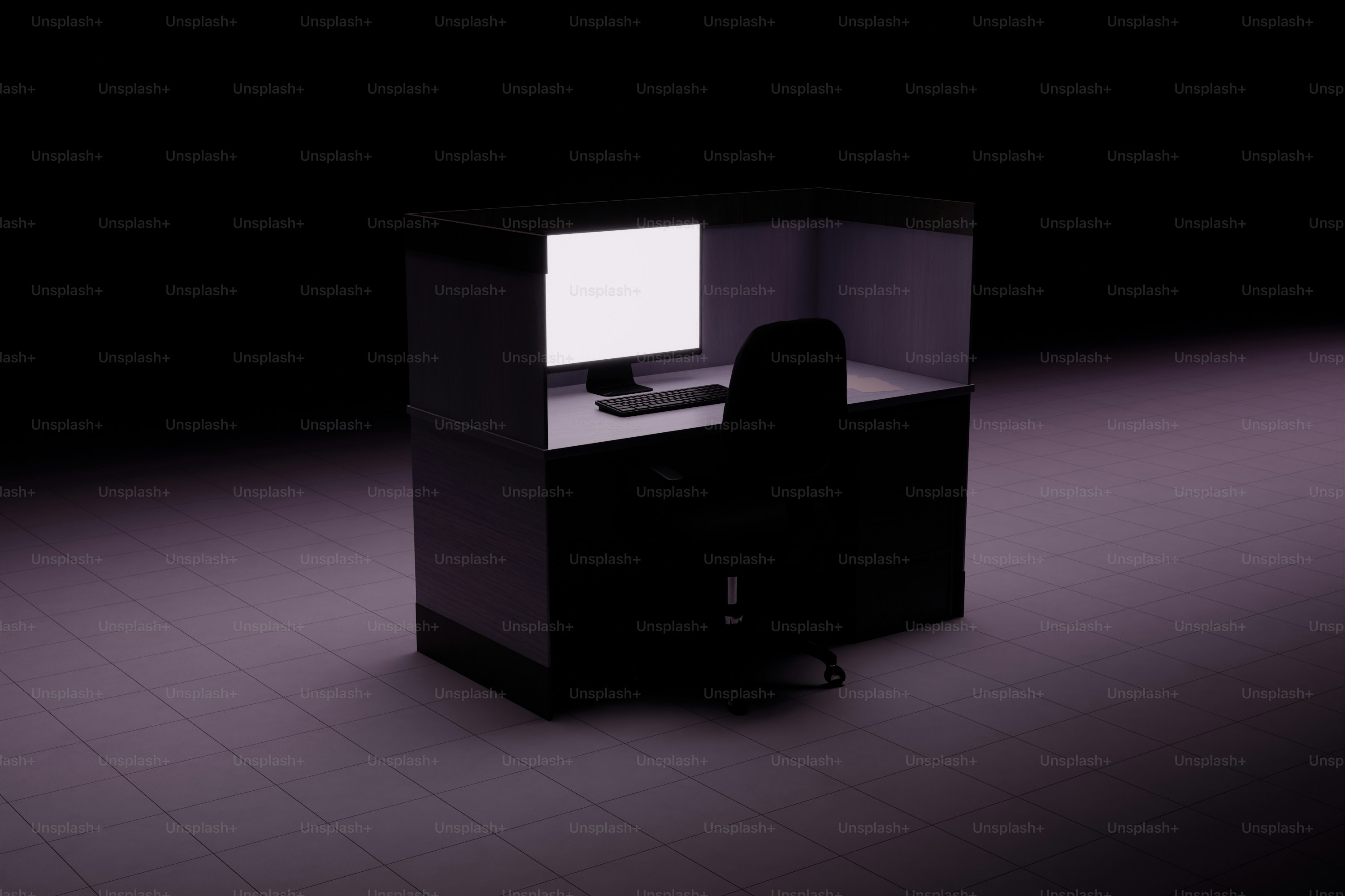 Um cubículo escuro de escritório com uma tela de computador iluminada.