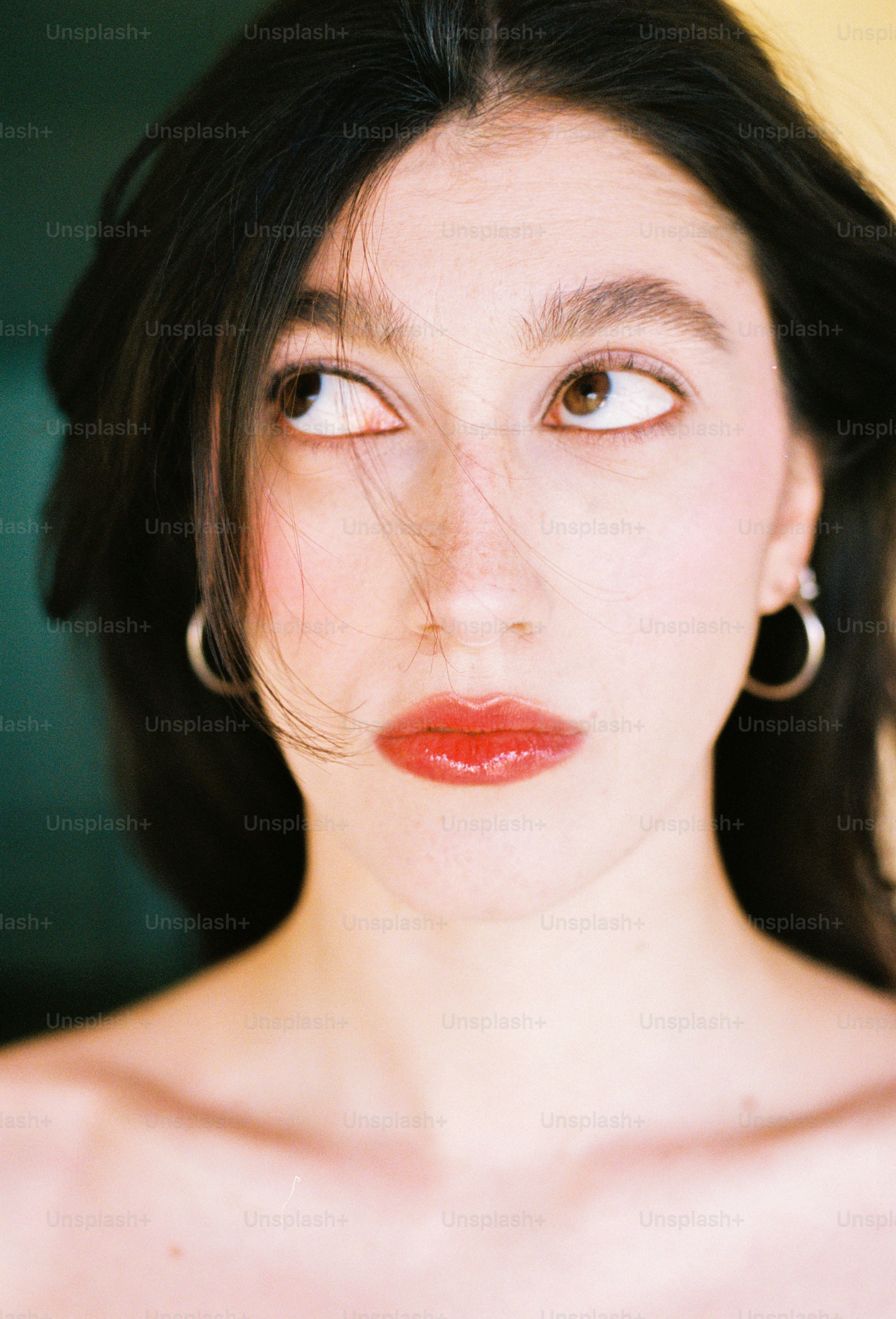Young woman with dark hair and red lipstick looks up