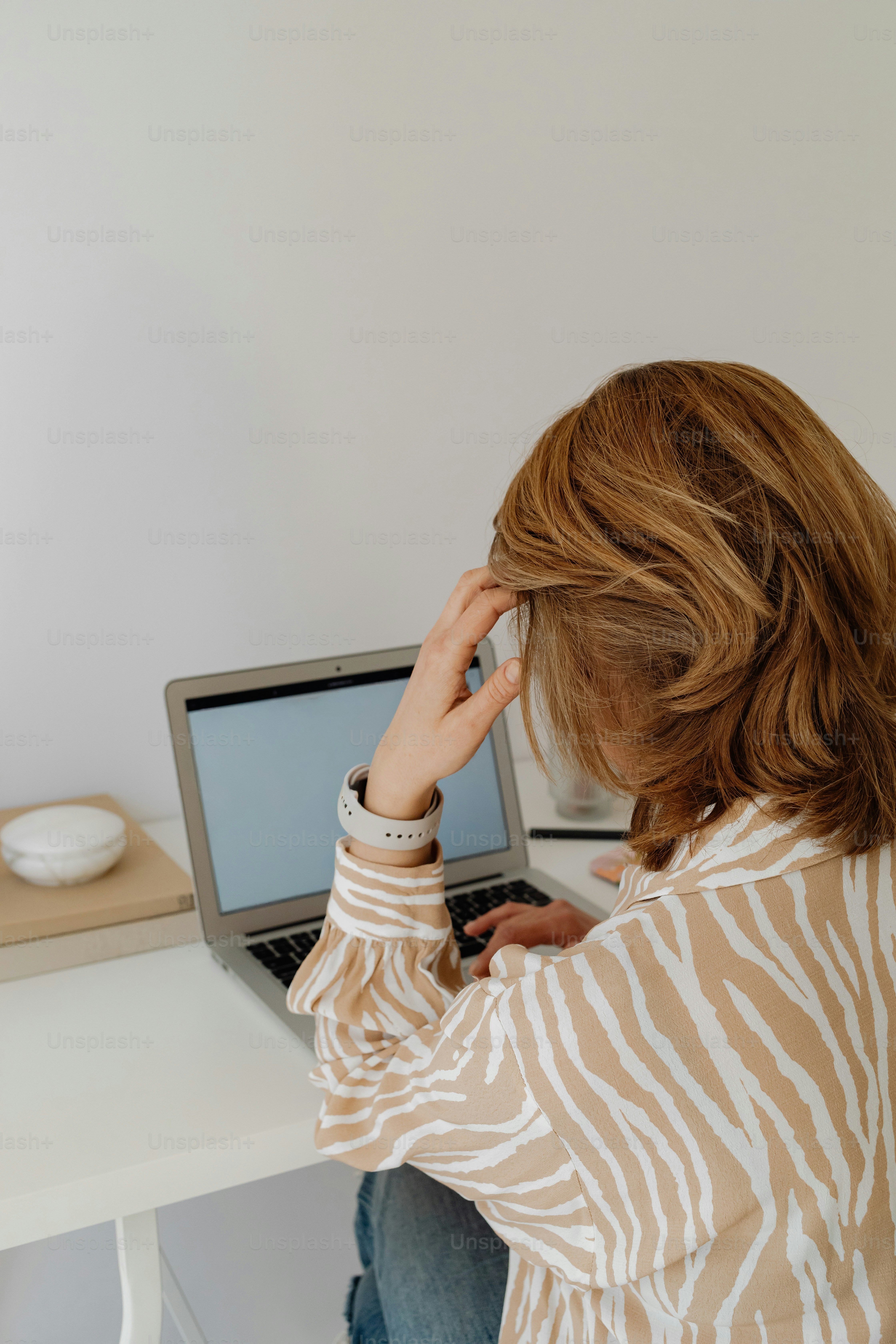 Wanita bekerja di laptop dengan tangan di rambut