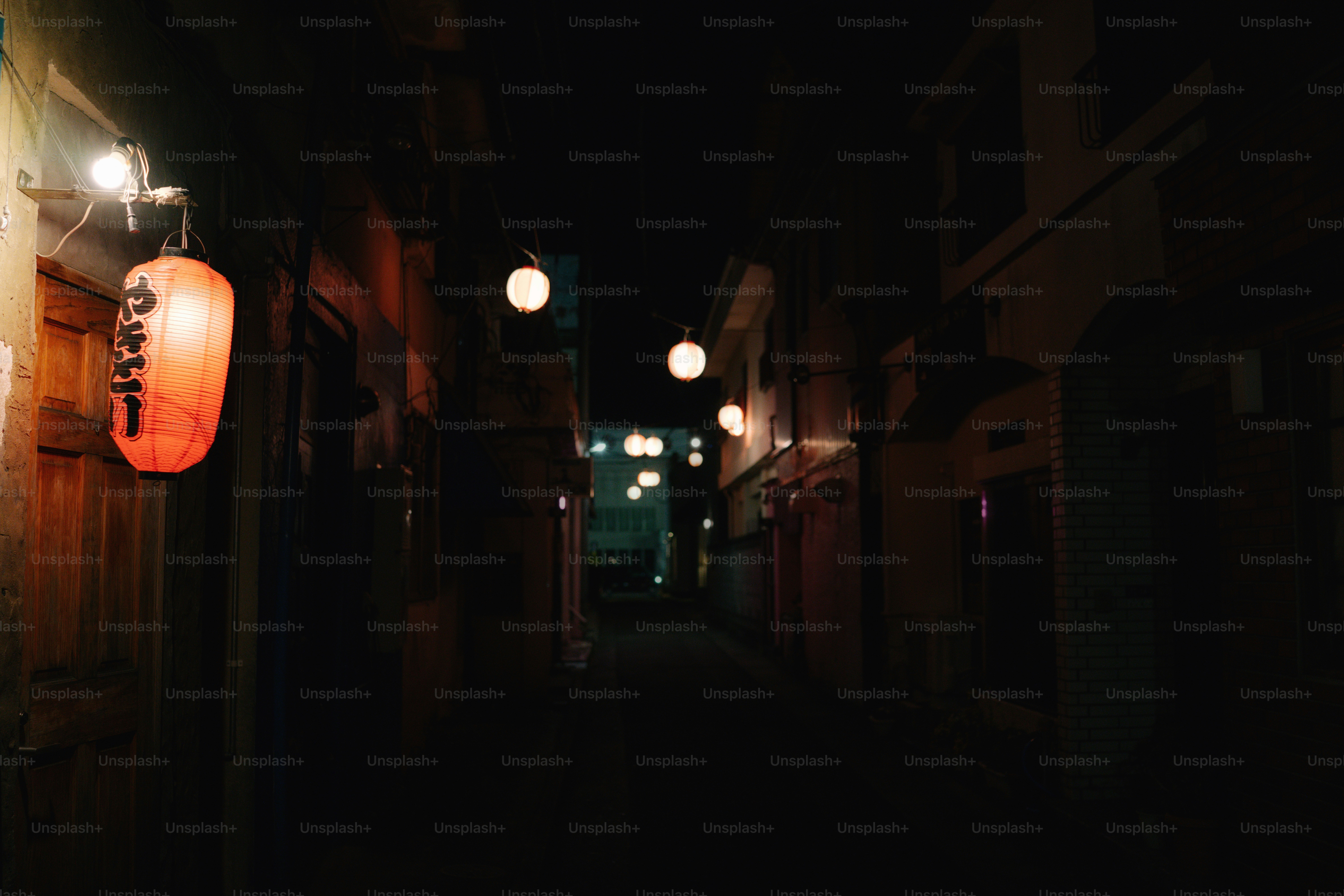 Eine dunkle Gasse mit leuchtenden Laternen in der Nacht.