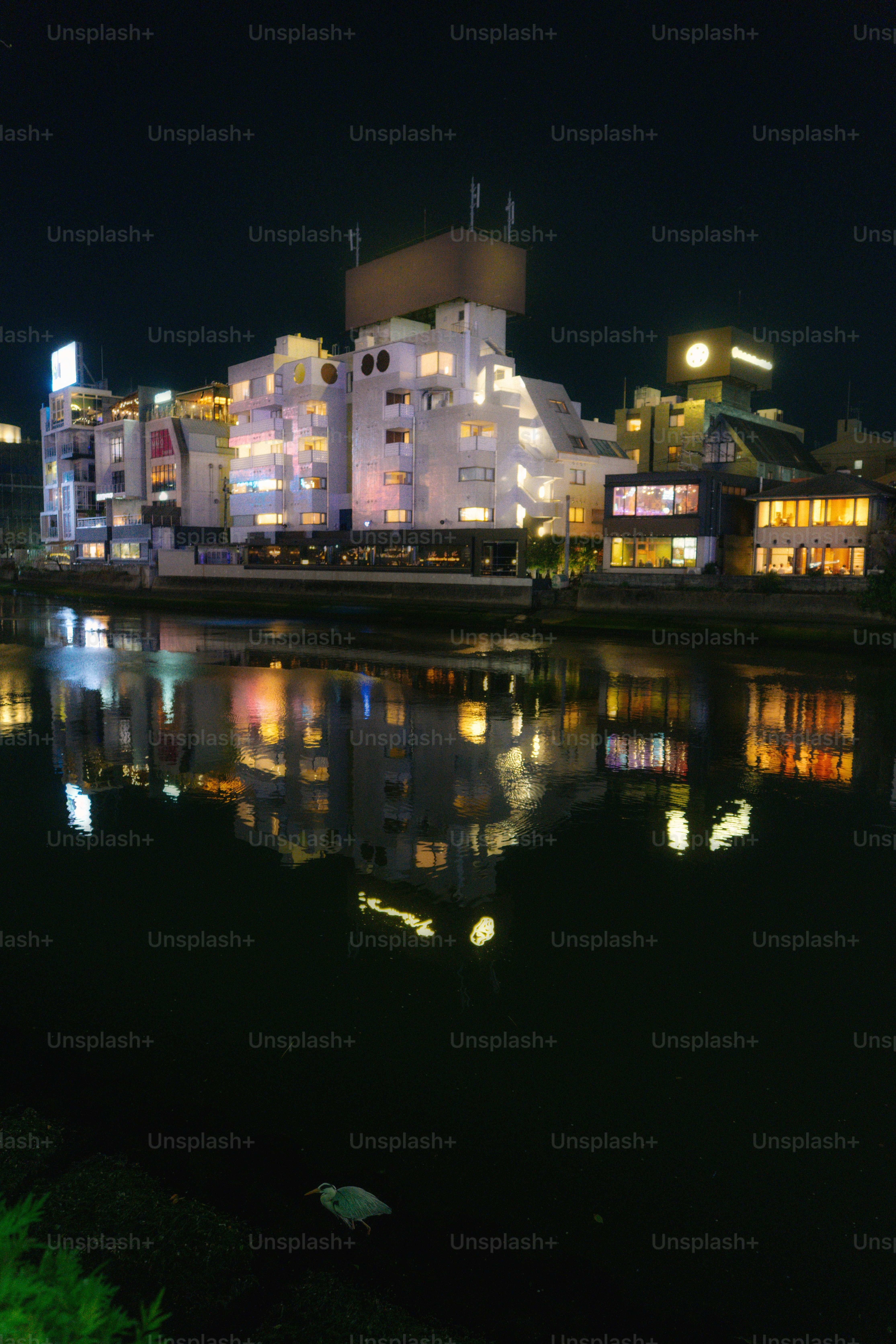 Gebäude, die nachts beleuchtet werden, spiegeln sich im Wasser