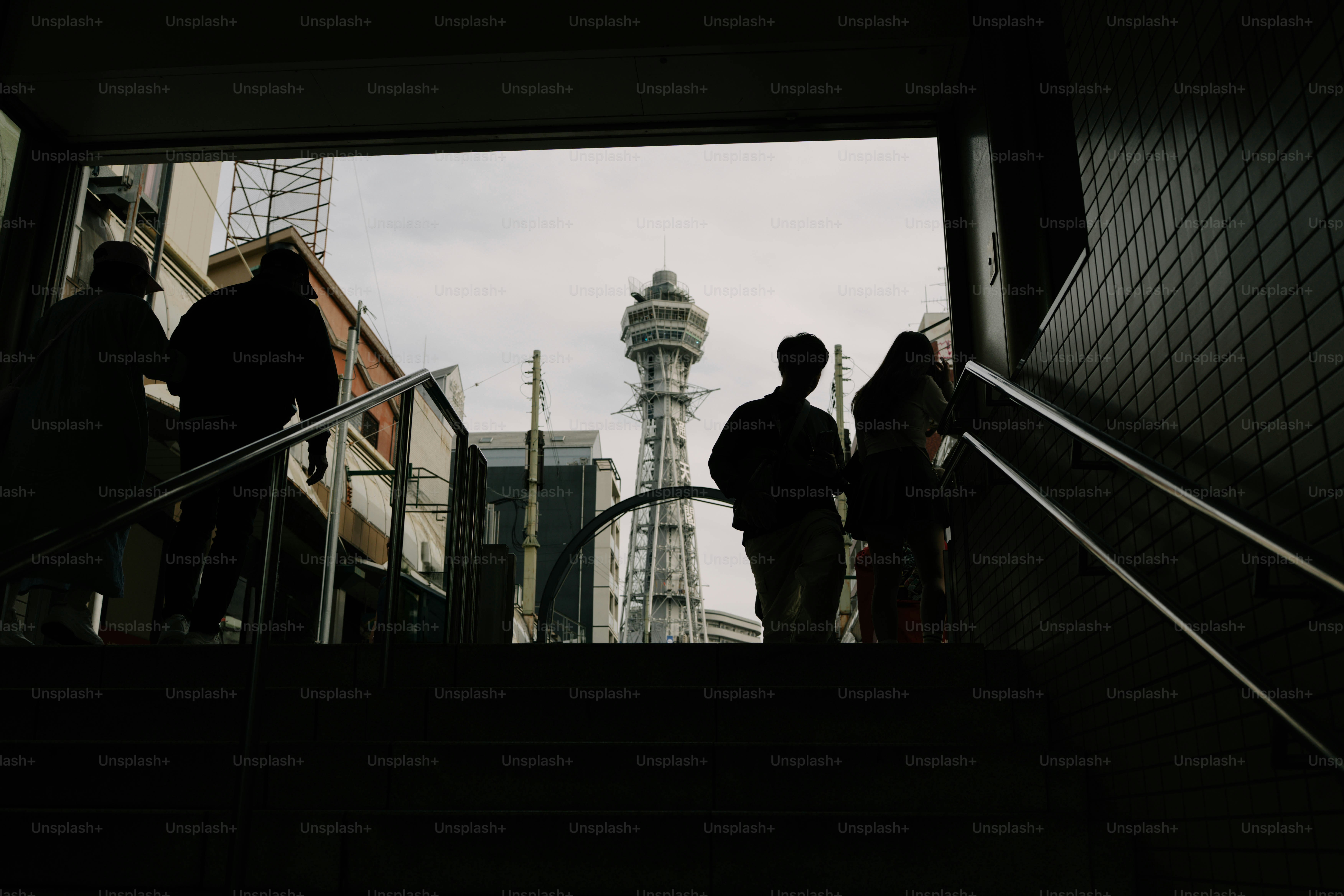 Silhouettes of people ascending stairs towards a distant tower.