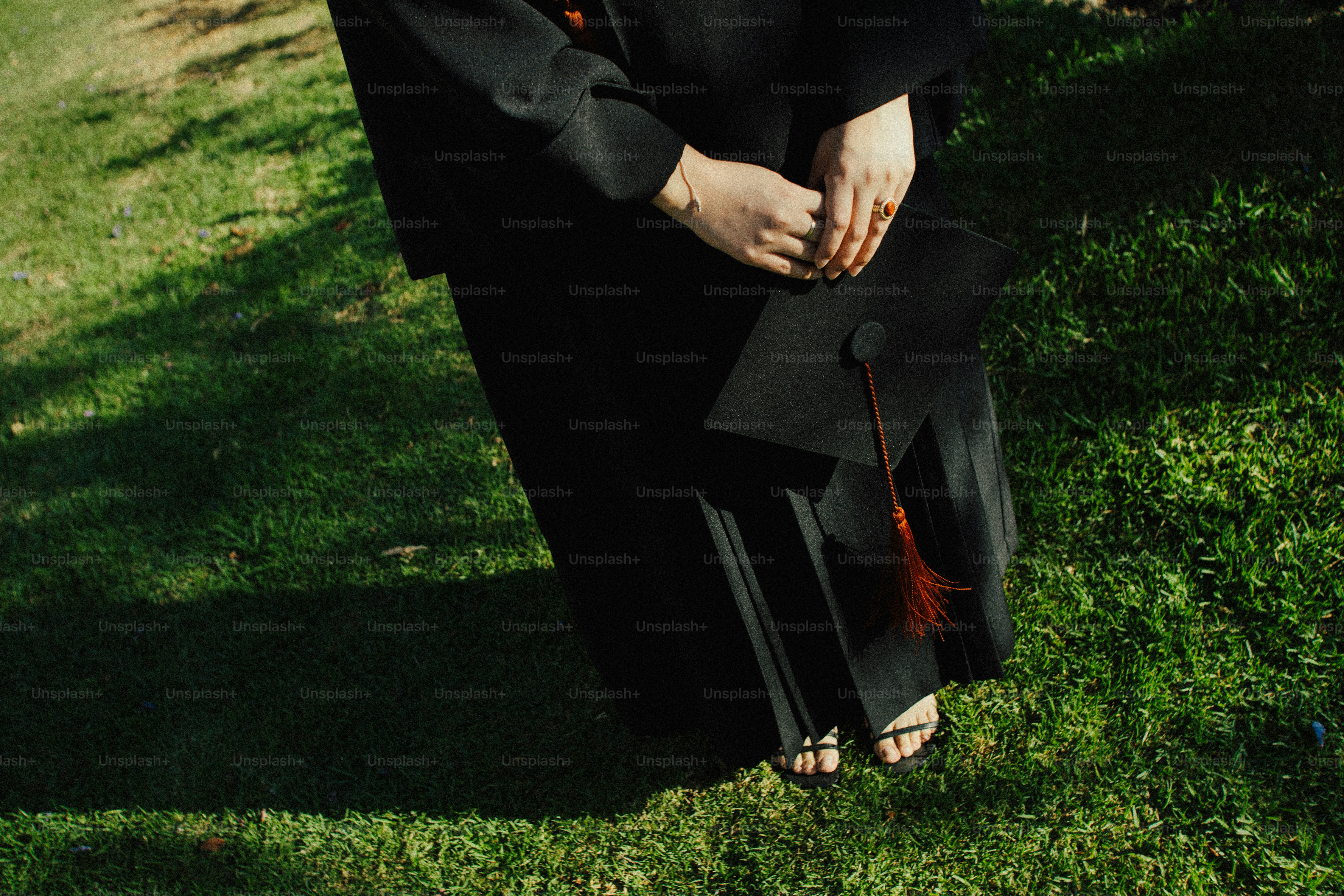 Graduating student in cap and gown holding graduation cap photo ...