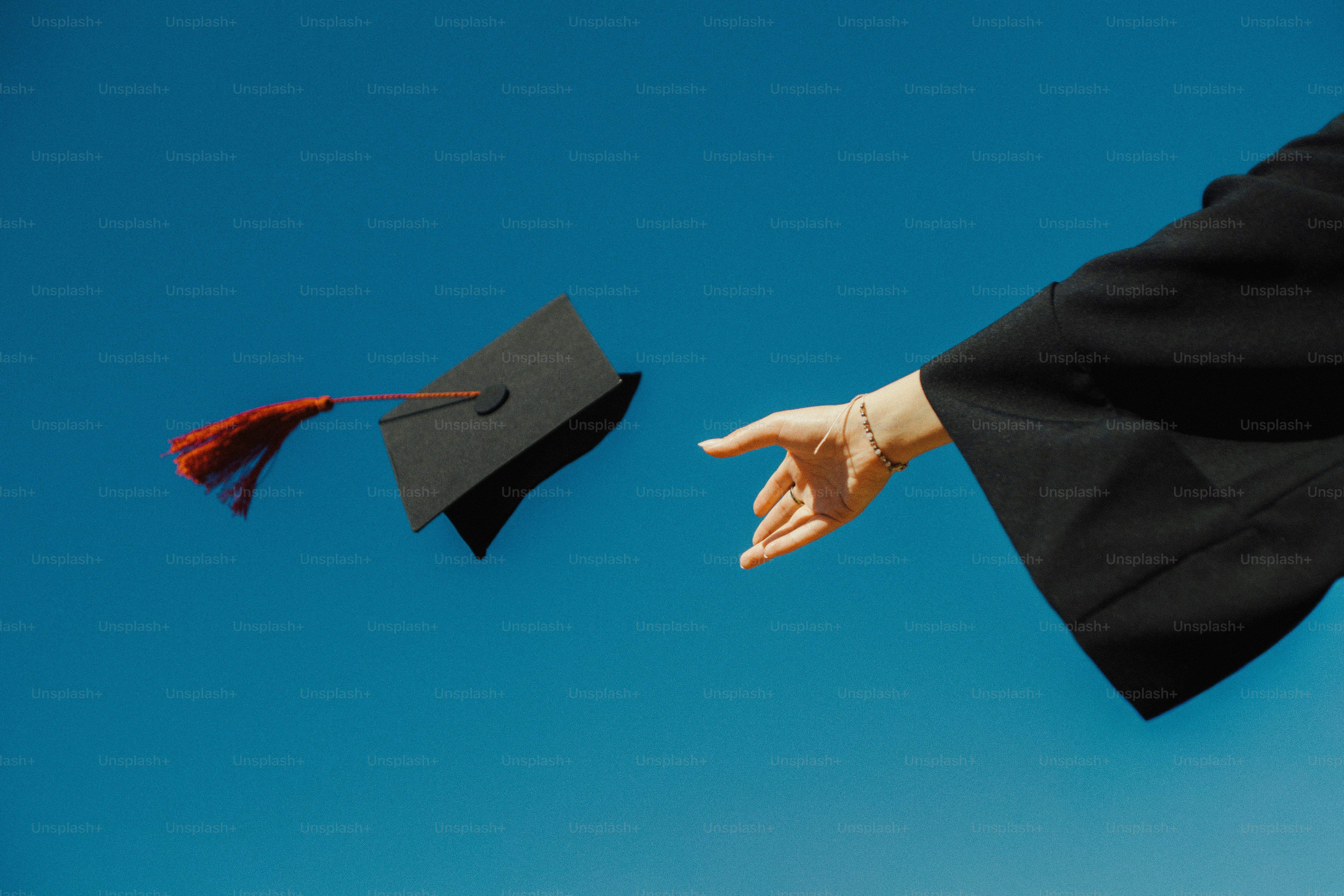 Graduation cap tossed in the air against blue sky