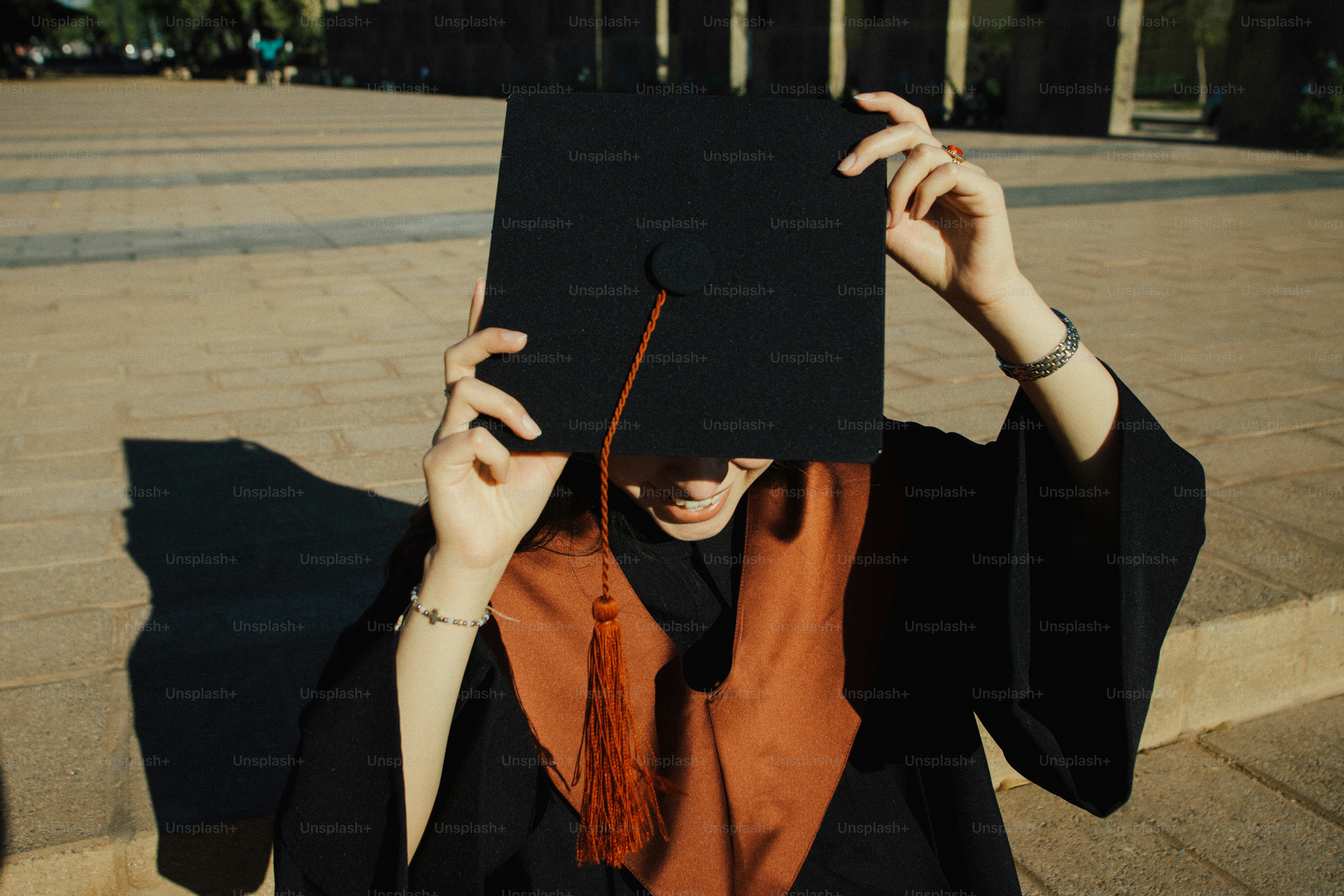 Graduating student in cap and gown holding graduation cap photo ...