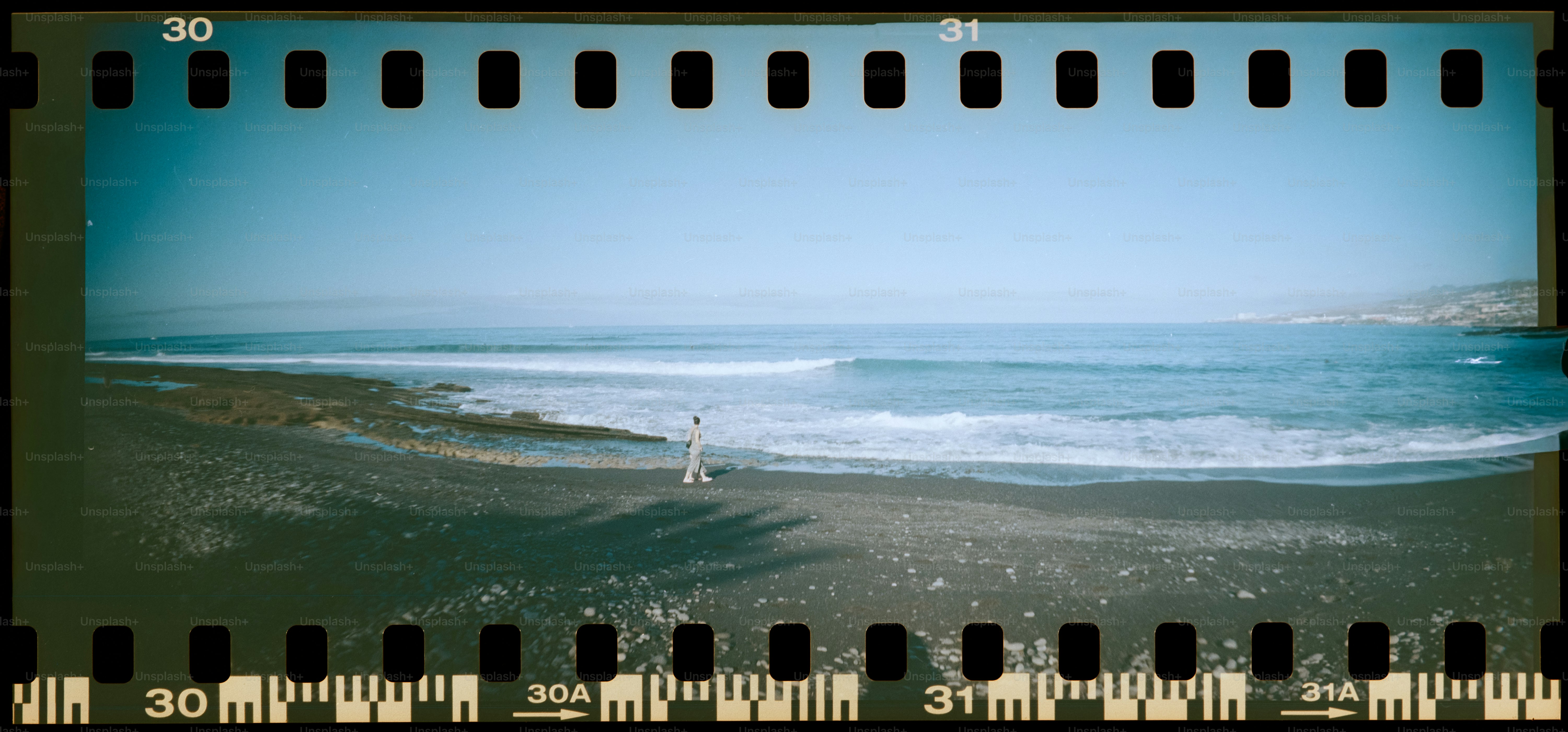 A person walks on a beach next to the ocean.