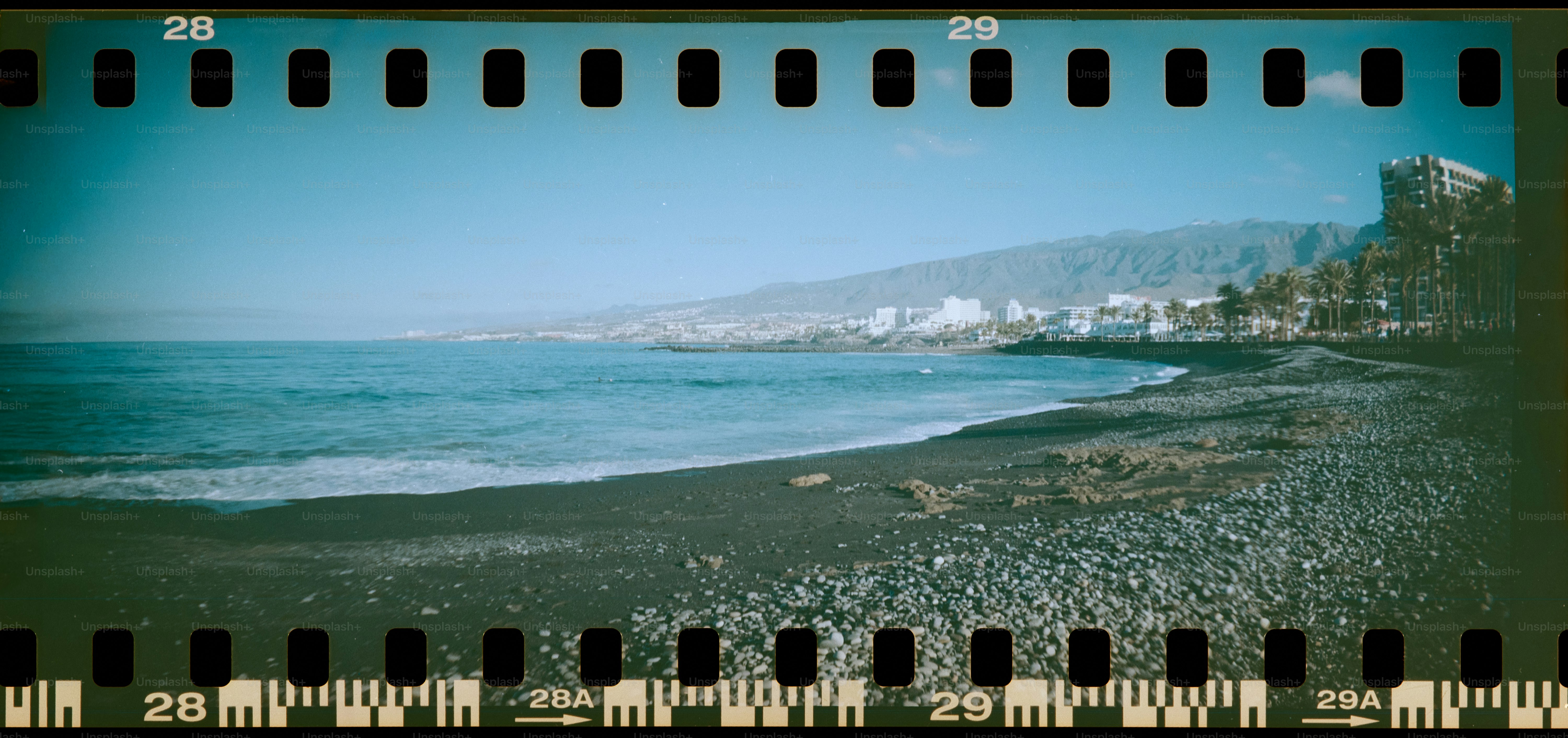 Rocky beach with ocean waves and distant town.