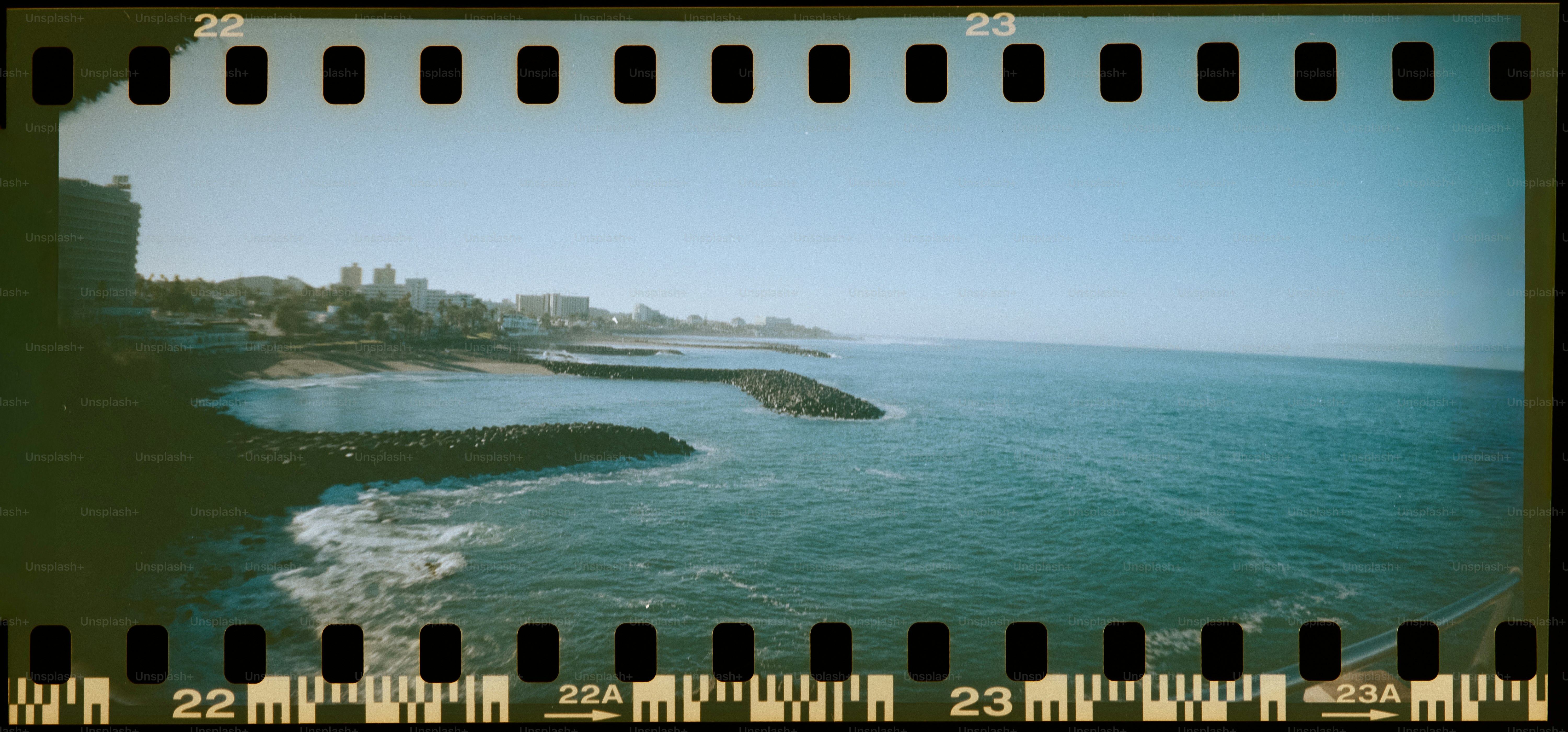 Waves crash on a rocky coastline under a clear sky.