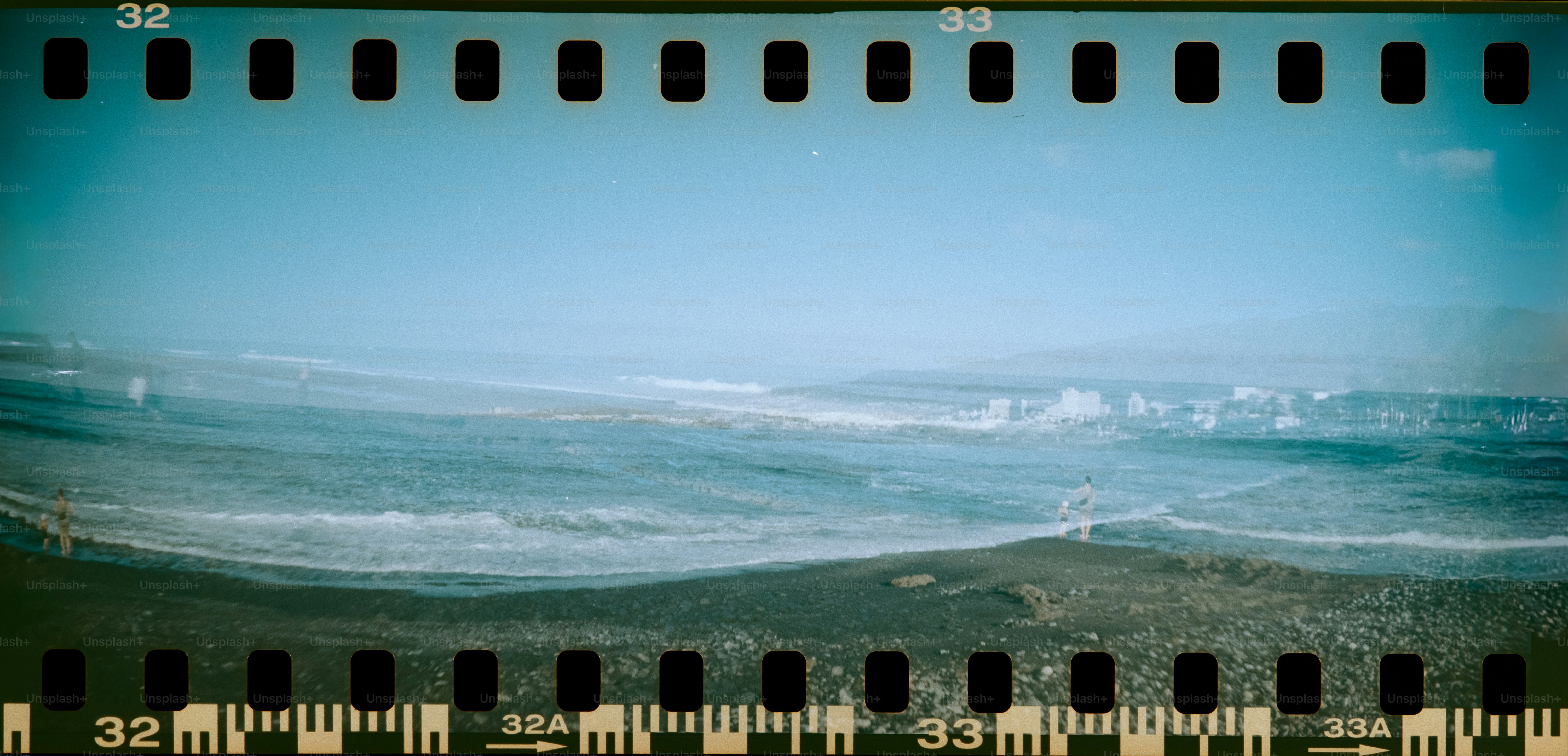 Waves rolling onto a sandy beach under a blue sky.