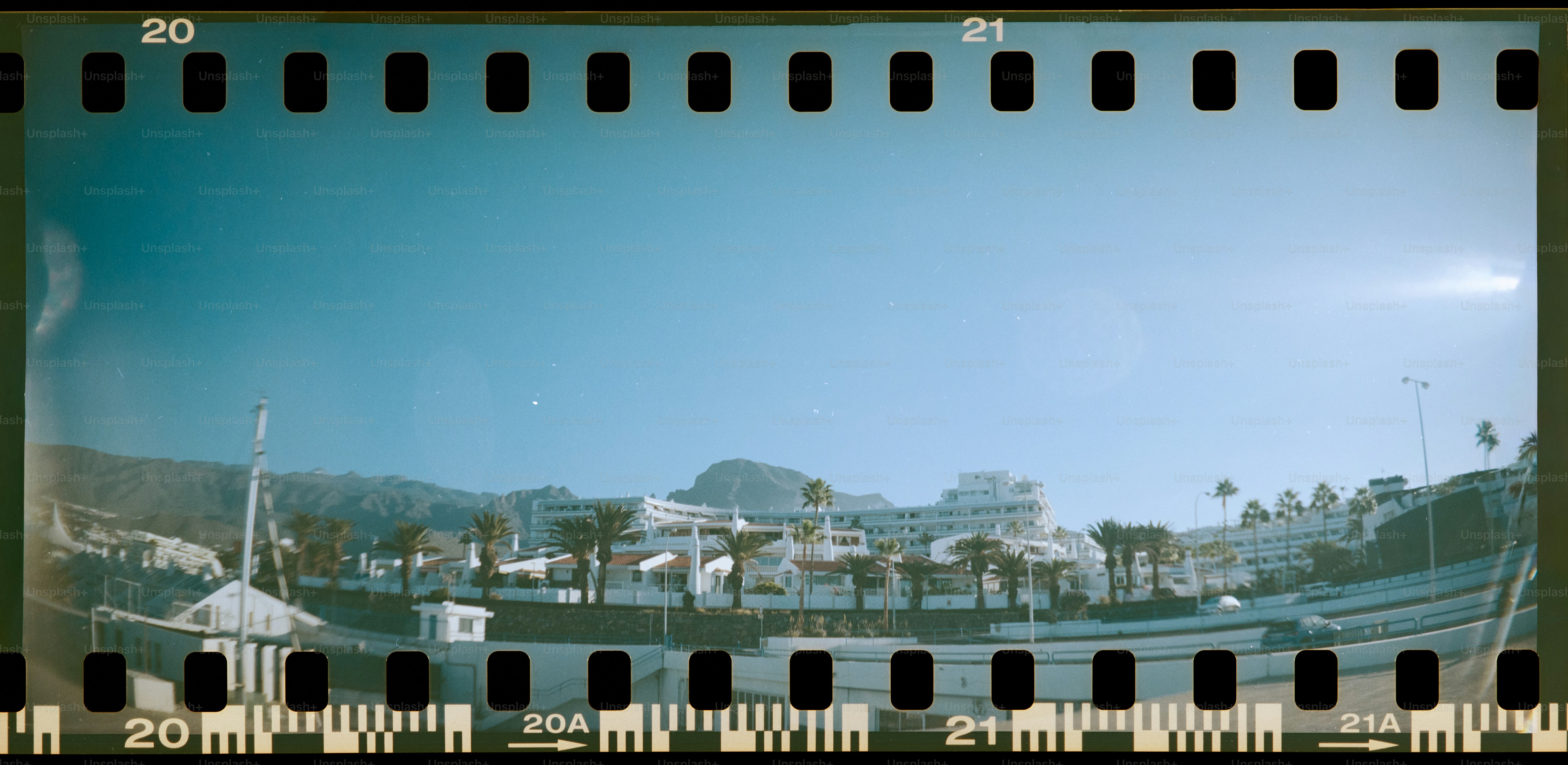 Buildings and palm trees under a clear blue sky.