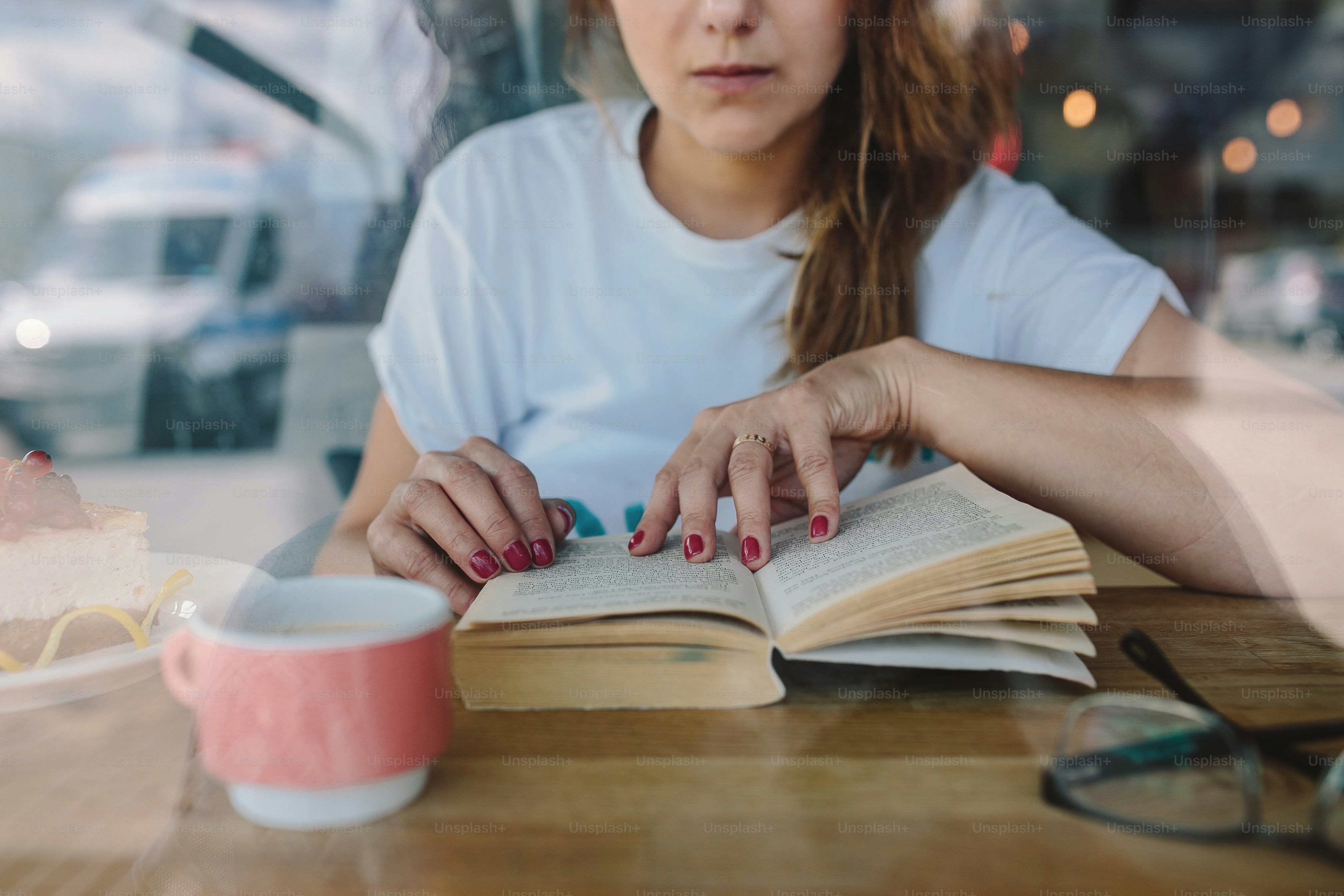 Wanita muda membaca buku di meja.