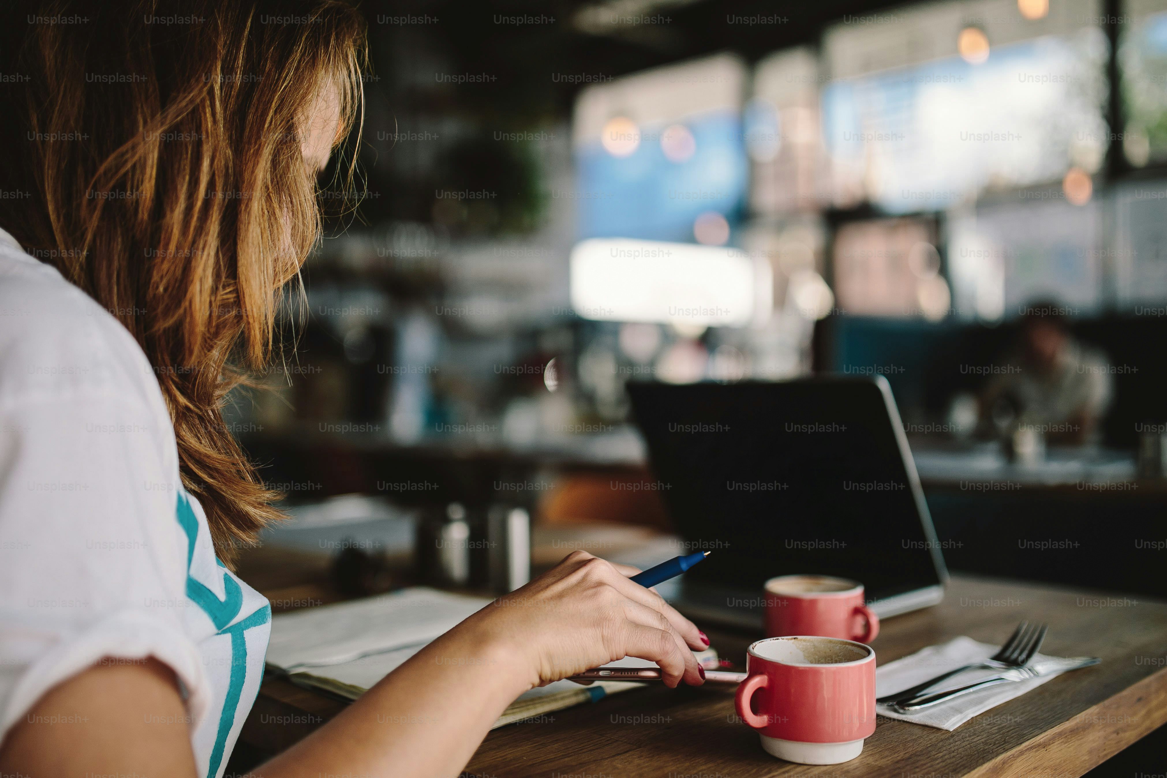 Wanita bekerja di laptop dengan kopi di kafe