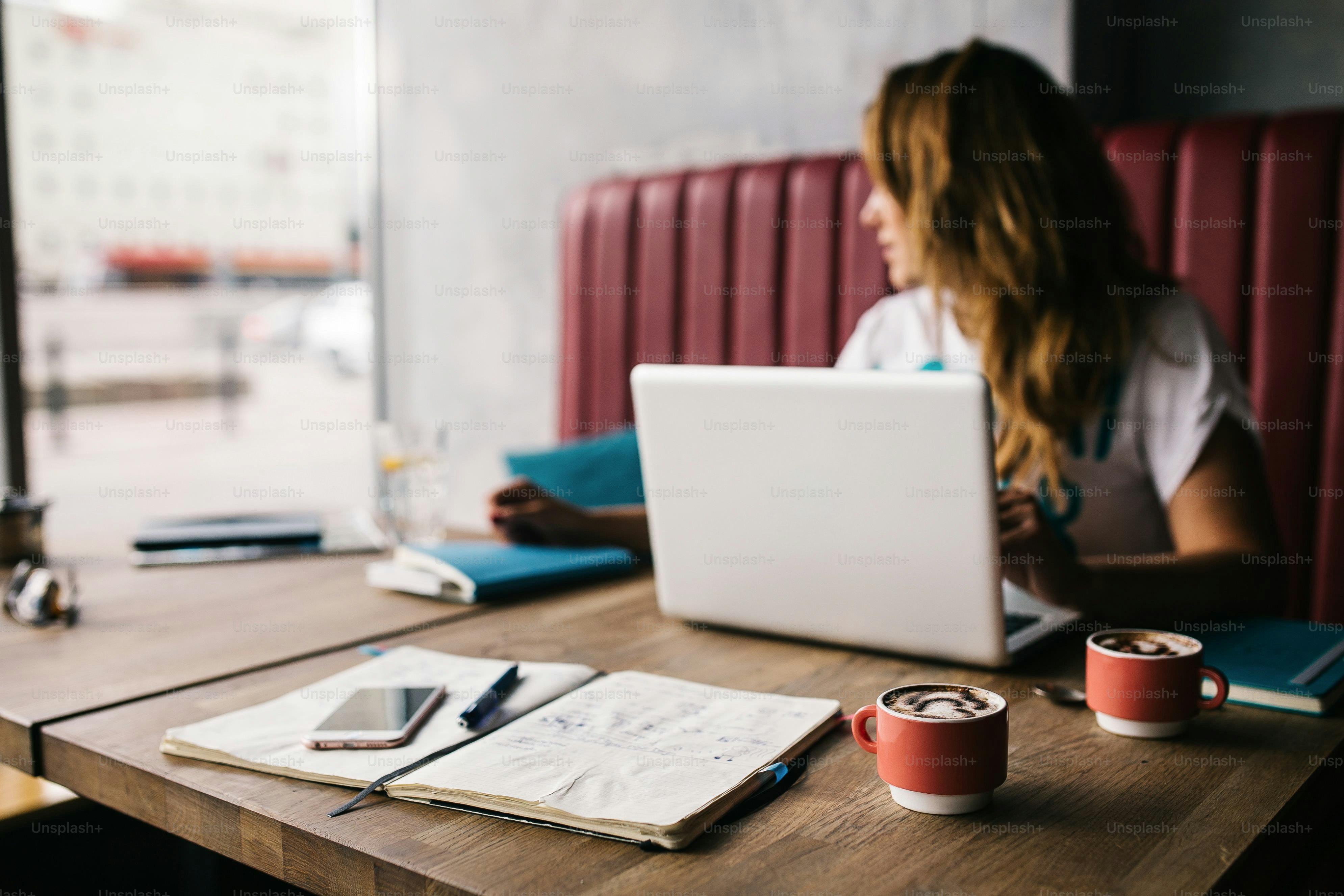 Wanita bekerja di laptop di kafe dengan kopi