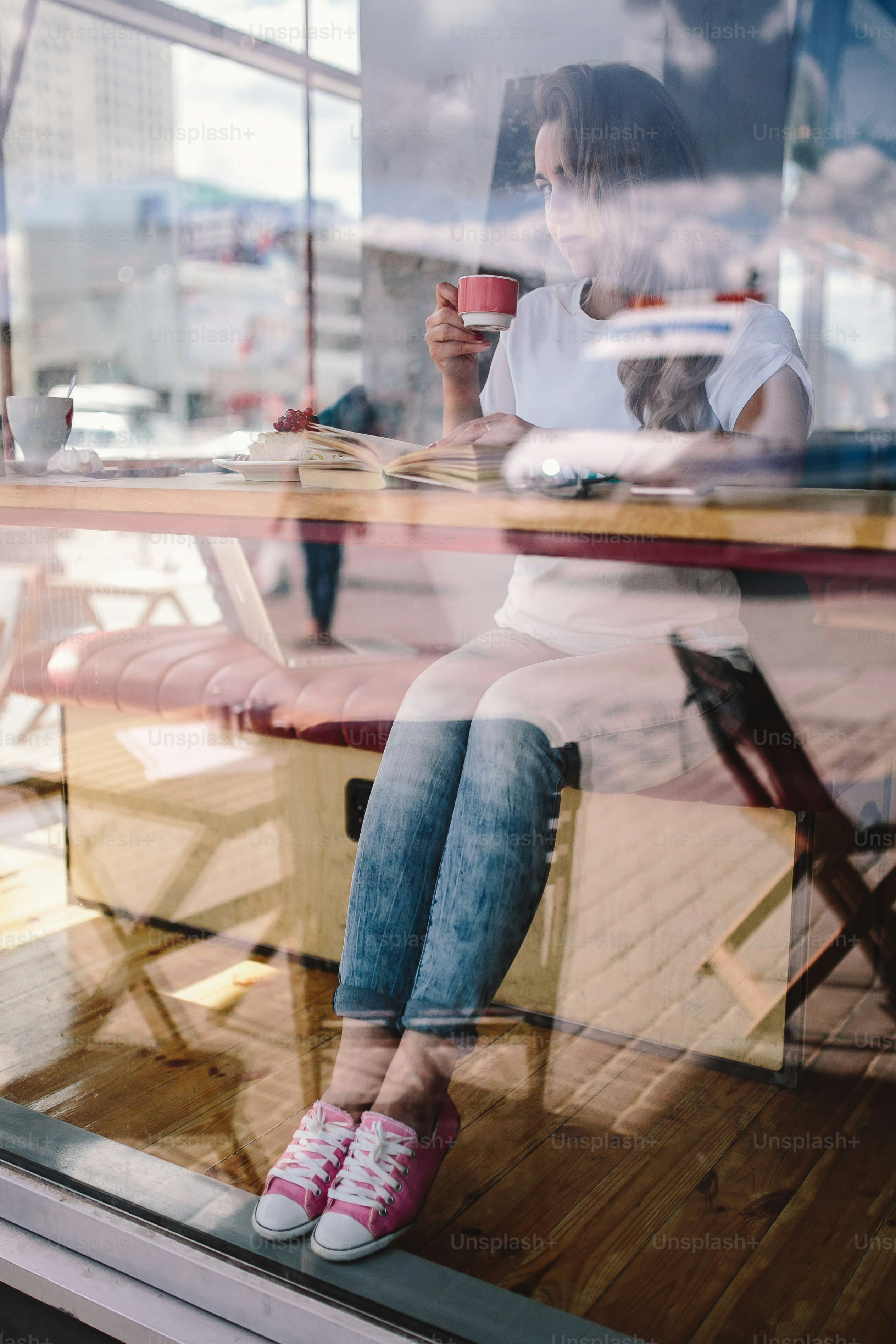 Wanita minum kopi di dekat jendela