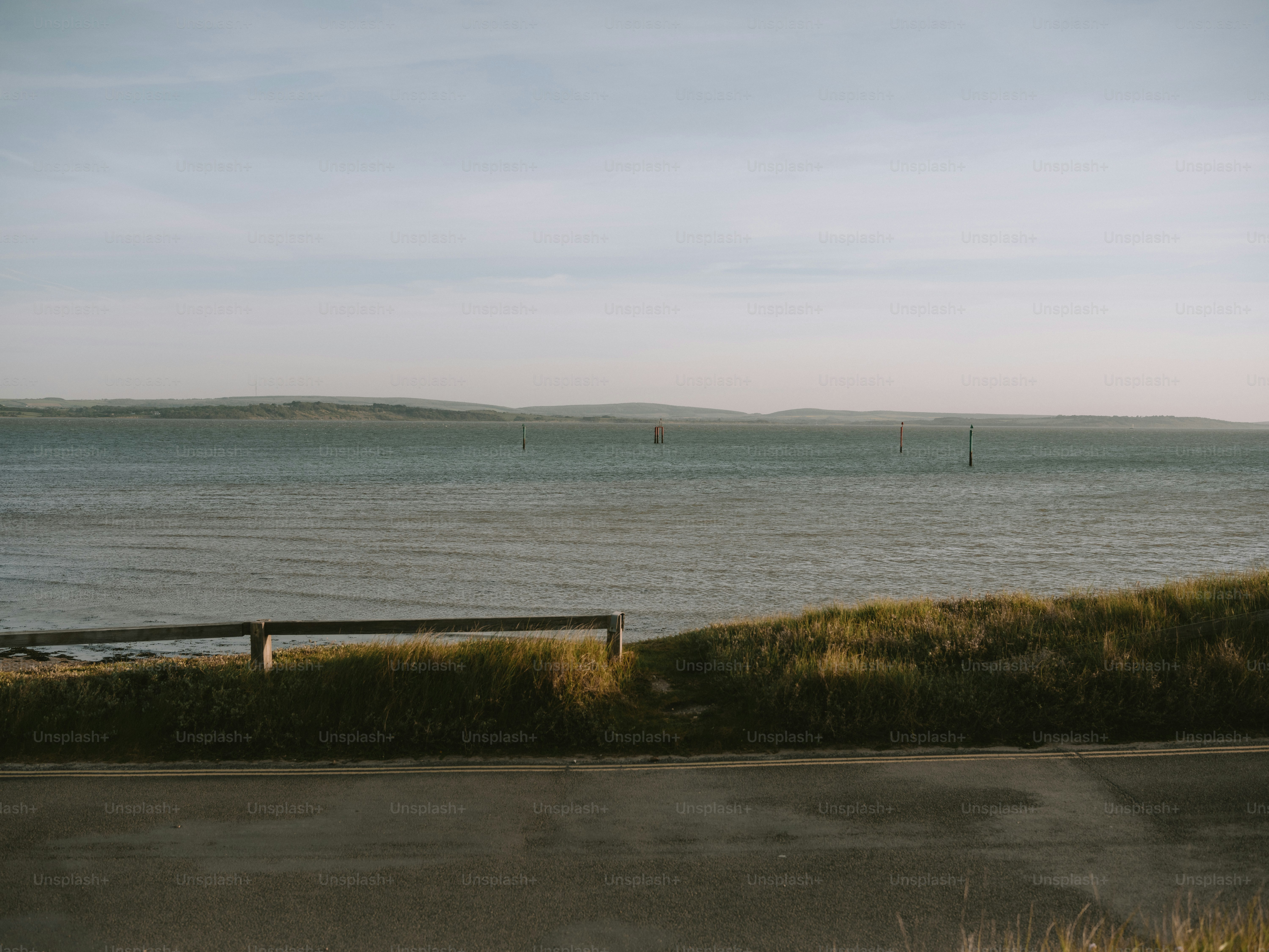 Calm ocean with distant hills under a hazy sky