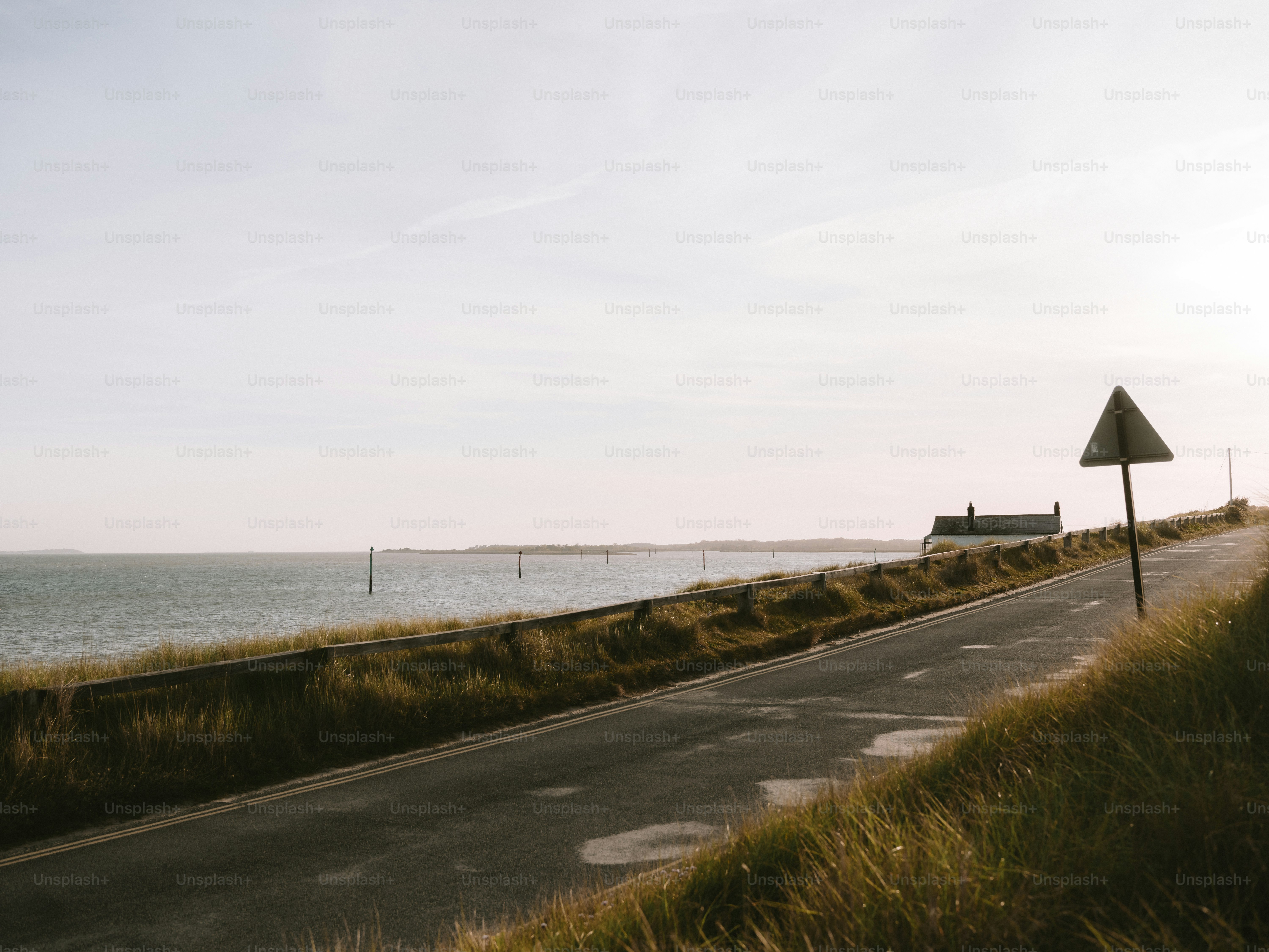 Coastal road with a house and a warning sign.