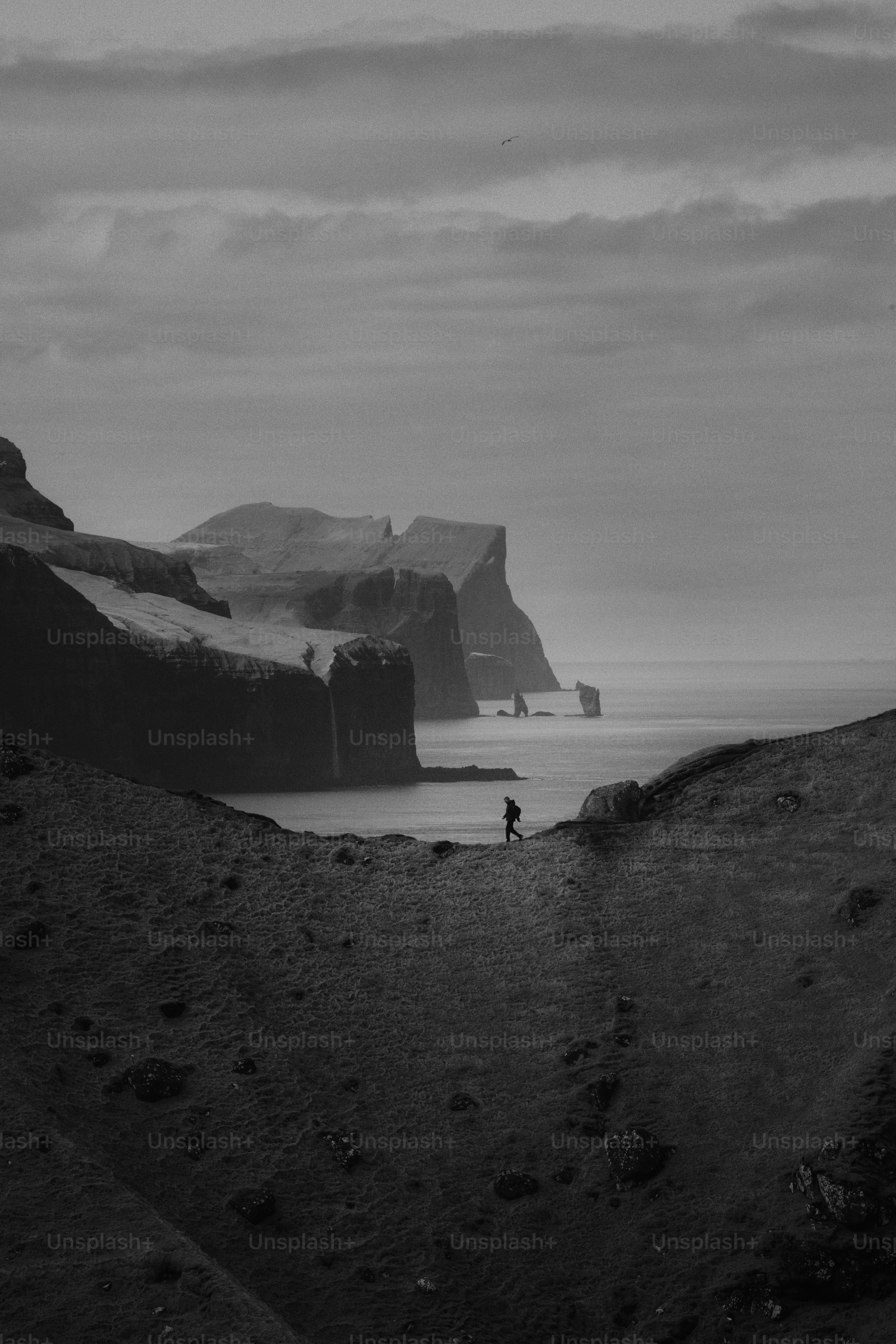 A lone hiker walks along a coastal cliff path.