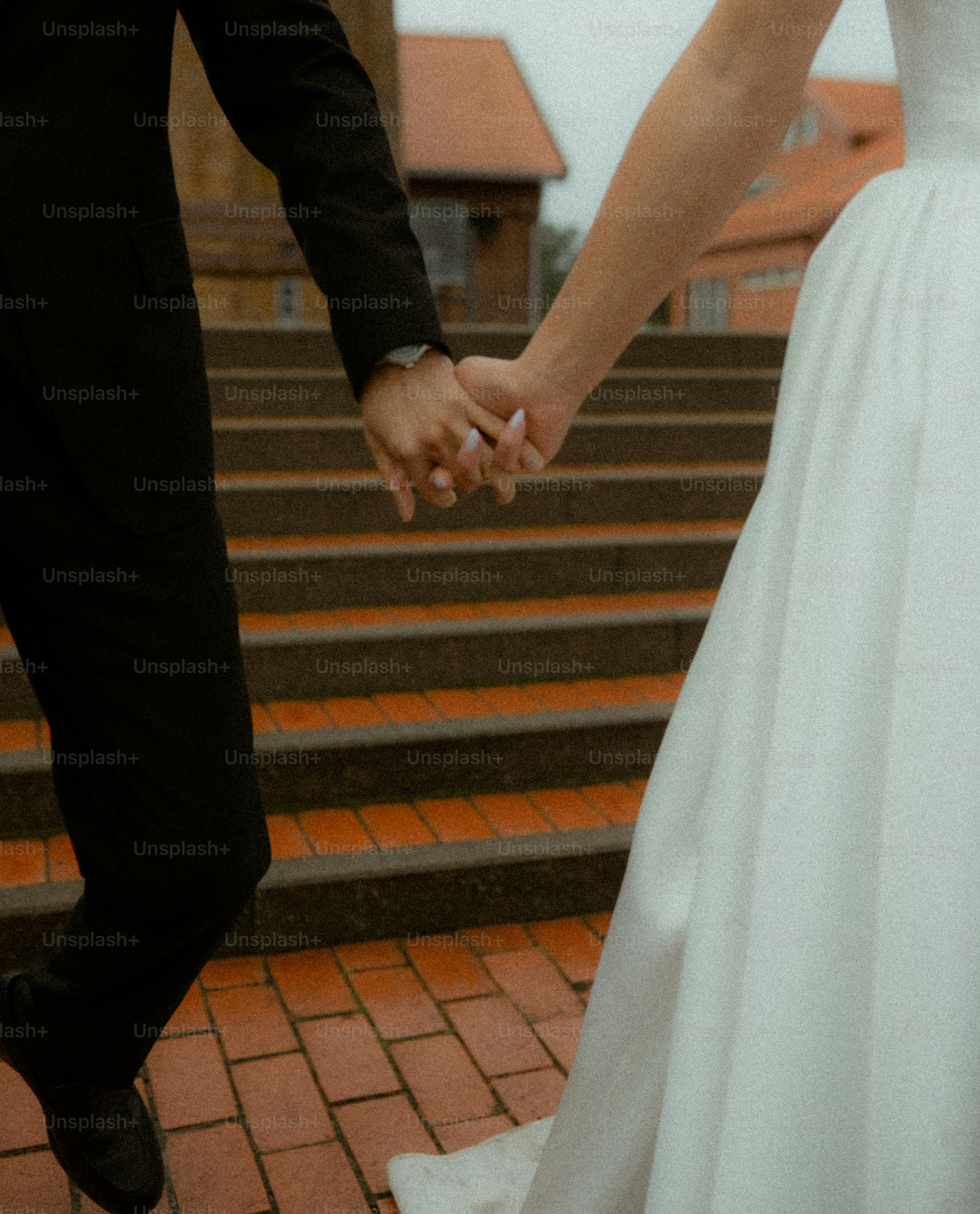 Recién casados cogidos de la mano subiendo escaleras