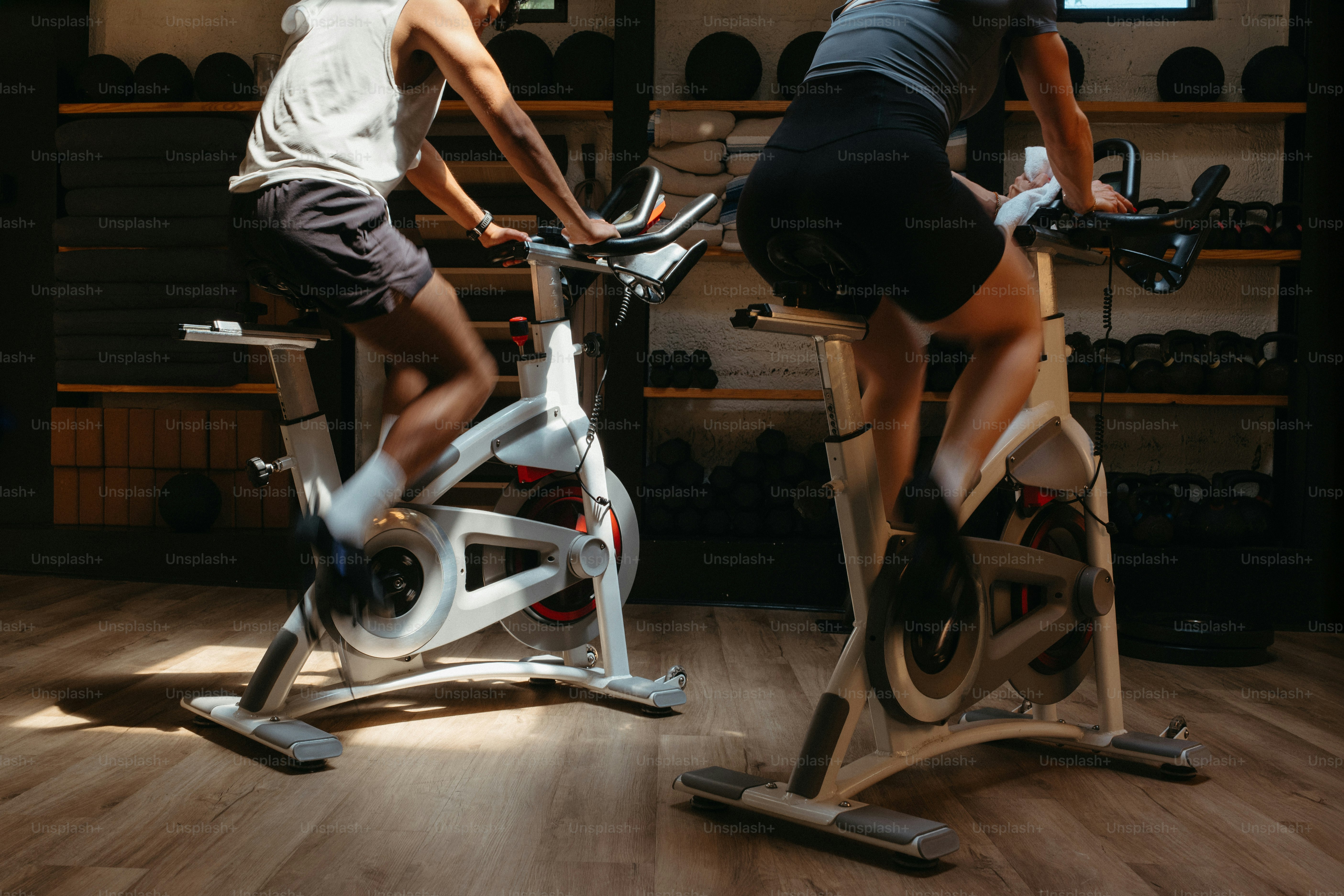 Zwei Personen, die drinnen auf Heimtrainern Fahrrad fahren.
