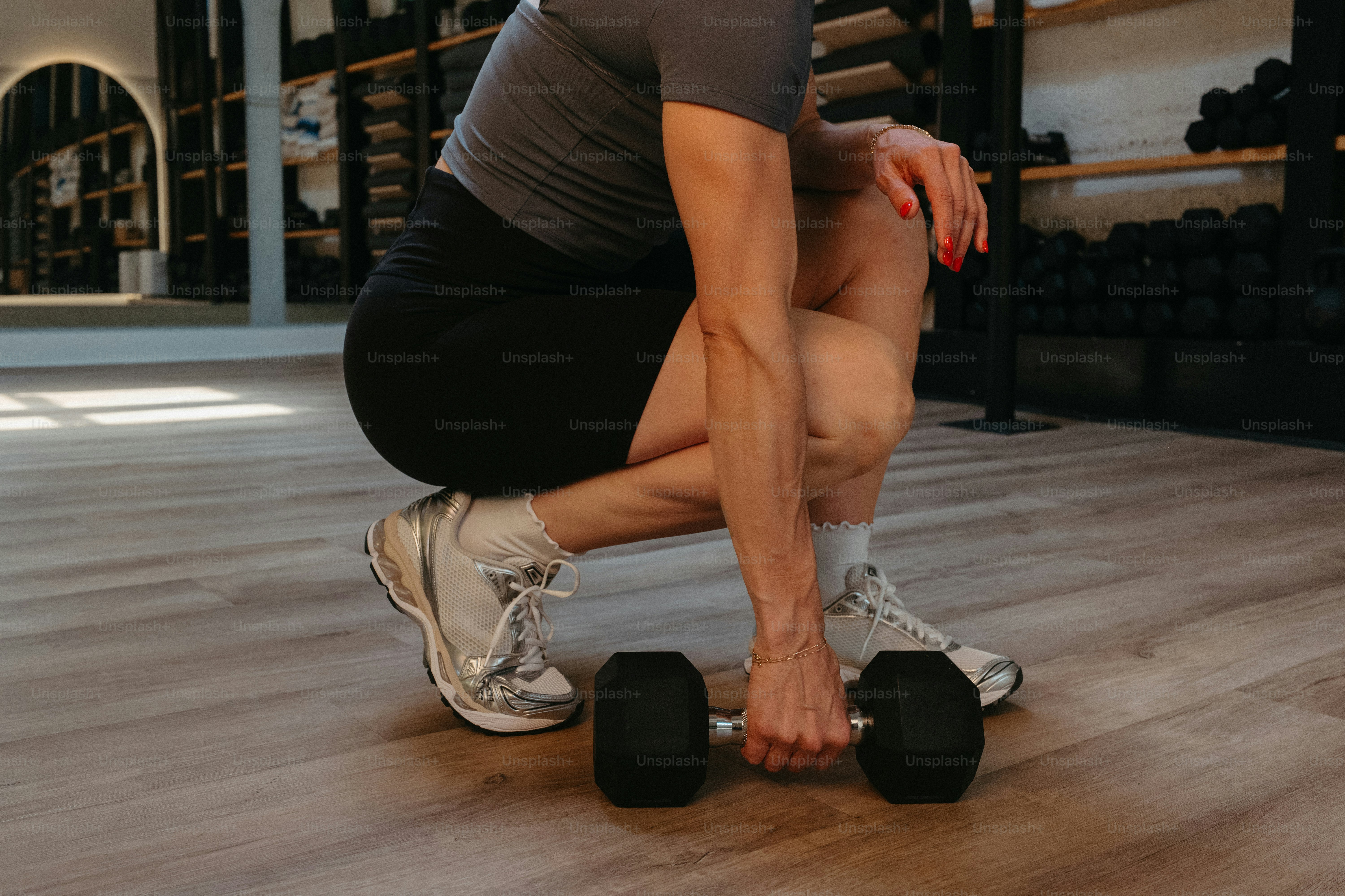 Person, die im Fitnessstudio eine Hantel hebt.