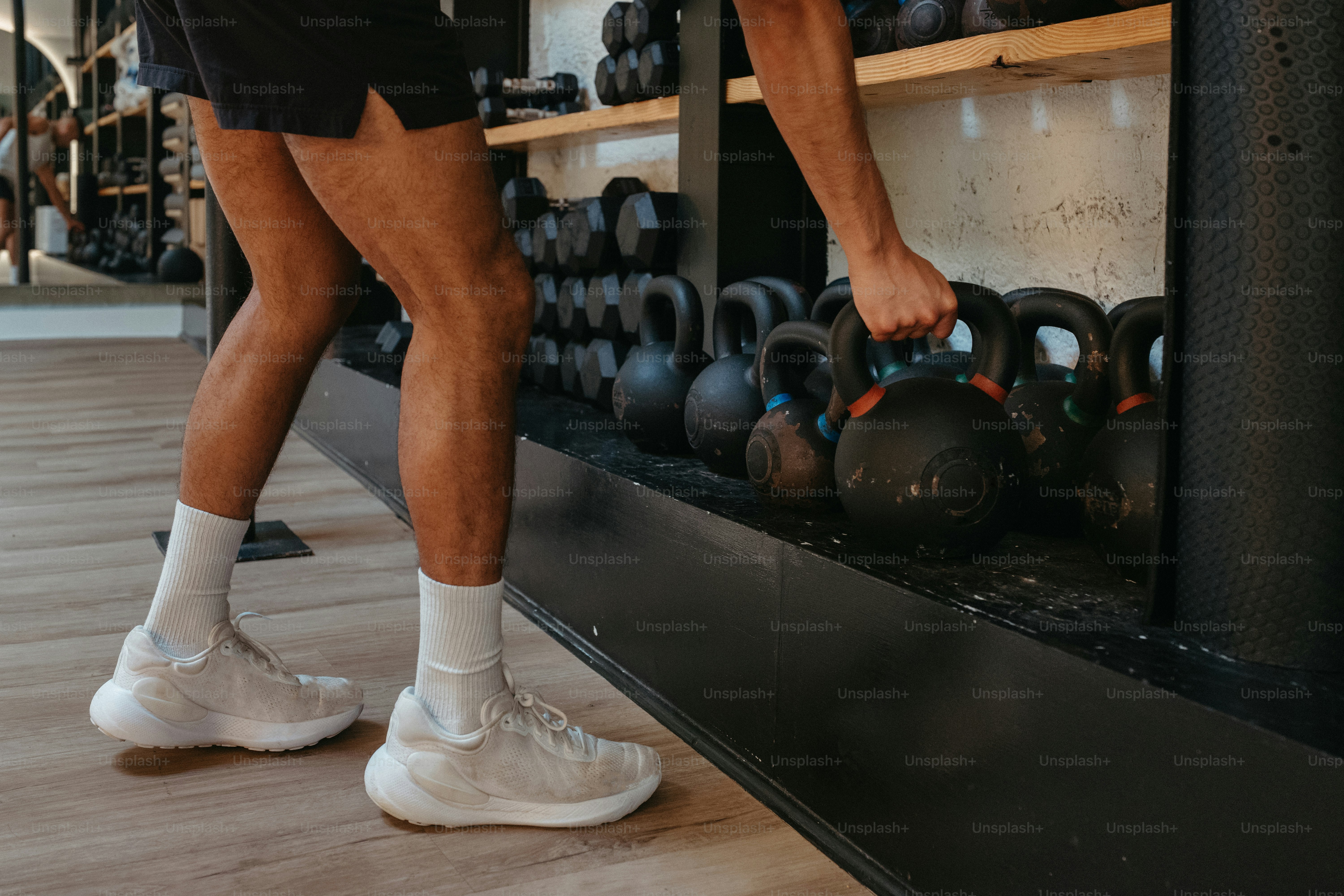 Person, die eine Kettlebell aus dem Regal nimmt.