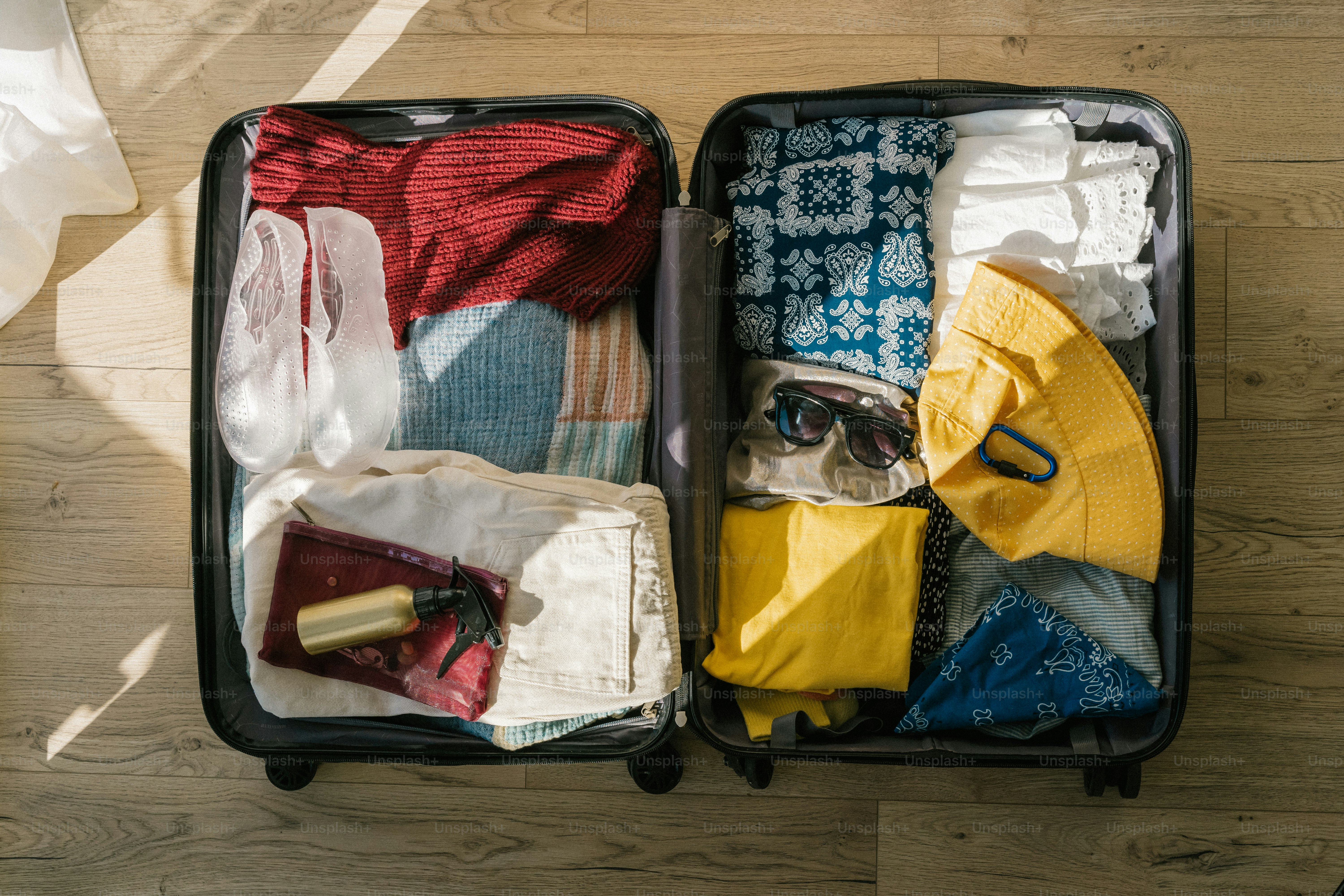 Open suitcase packed with clothes and accessories for travel.