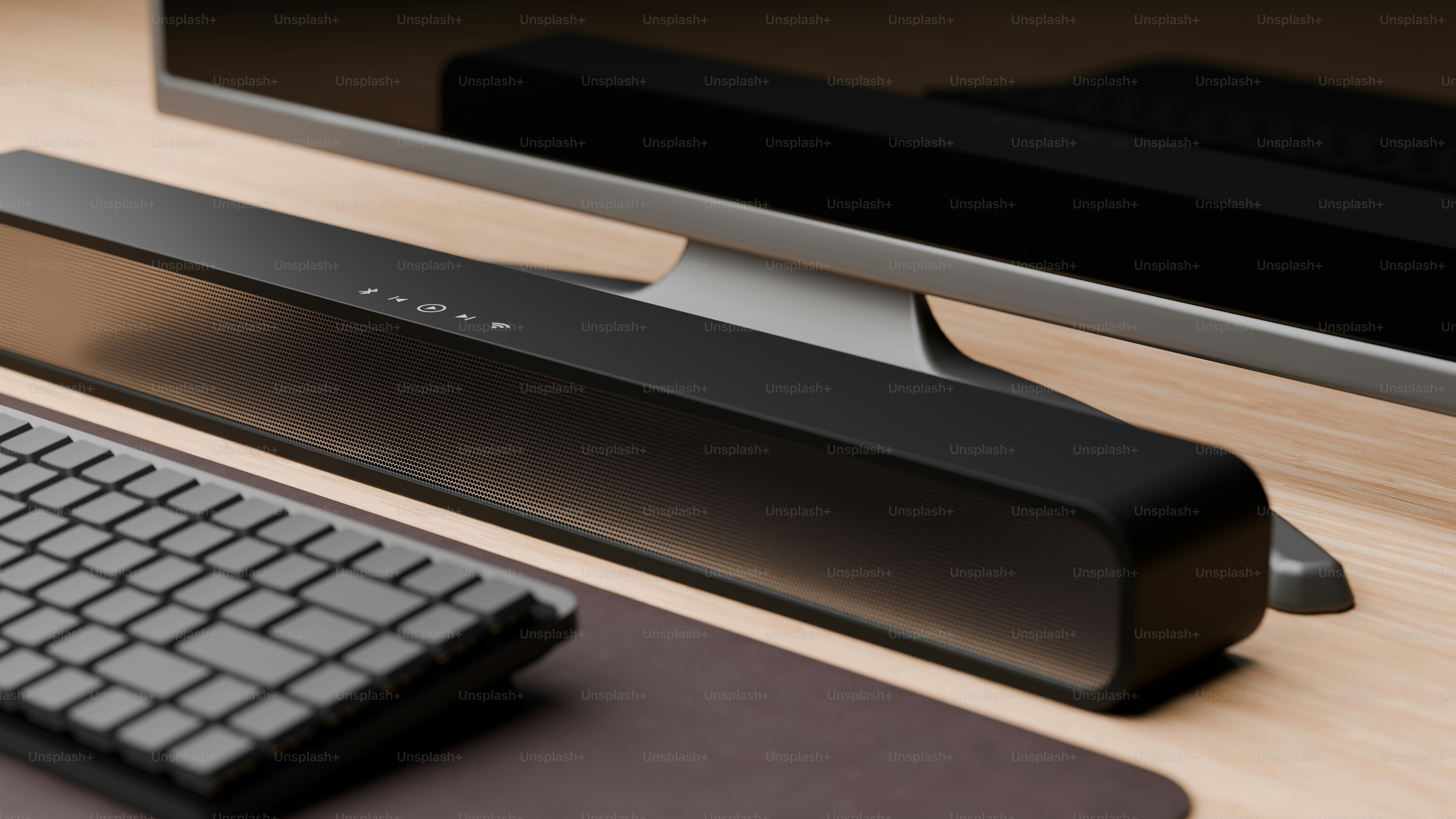 Black soundbar sits on a wooden desk with keyboard. photo – Keyboard ...