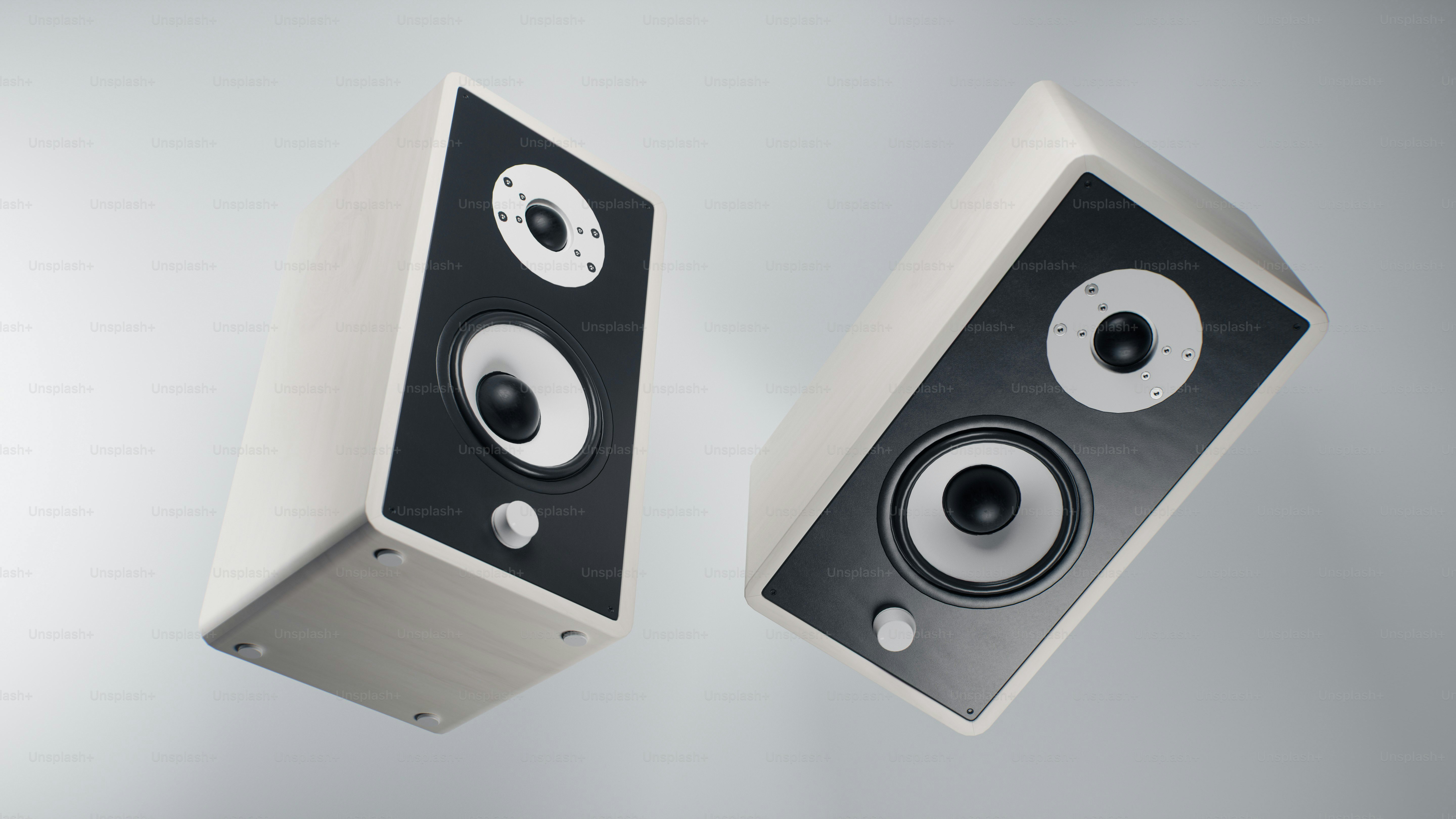 Two white and black speakers floating against a gray background
