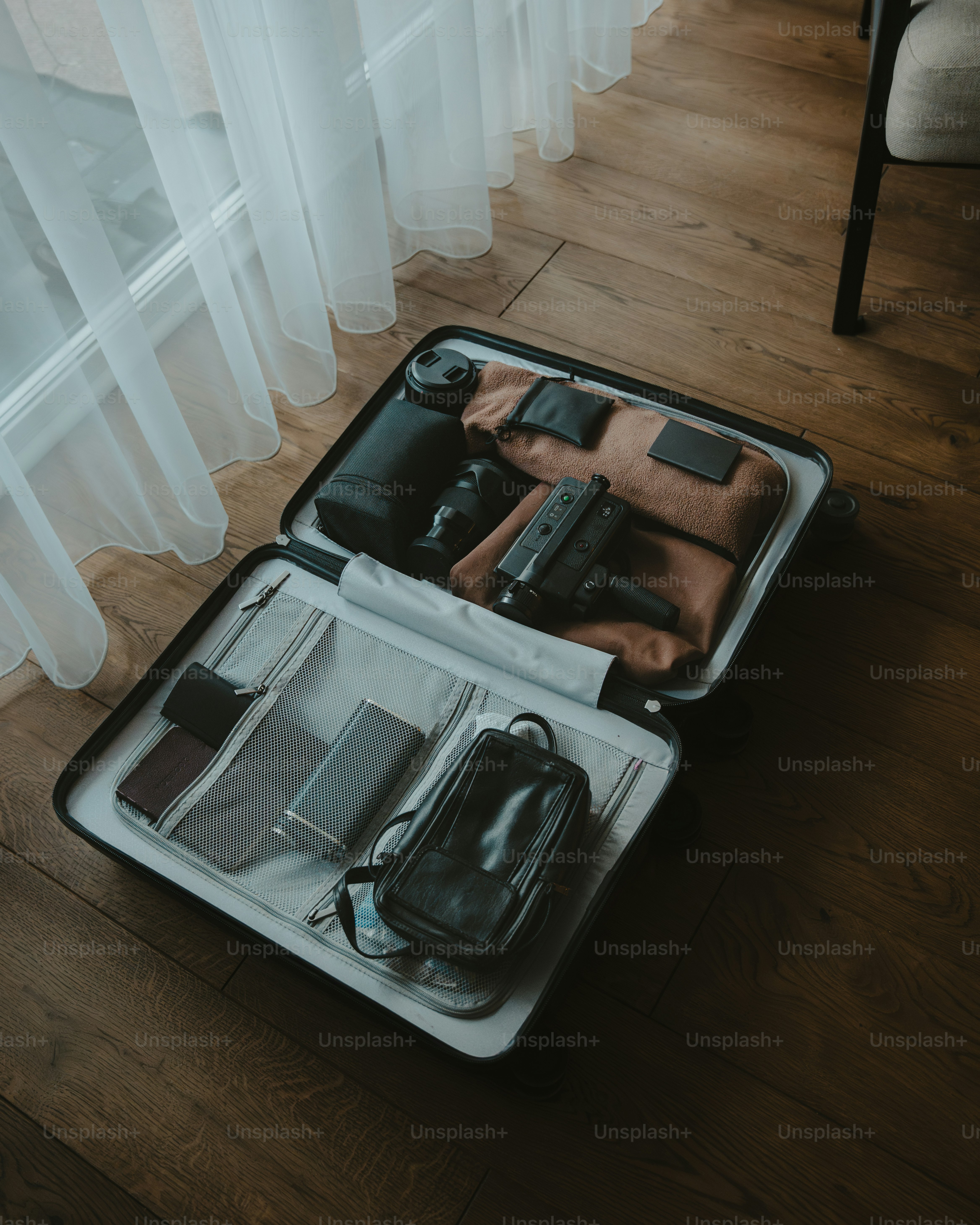 Abre la maleta llena de material fotográfico y artículos esenciales para viajar.