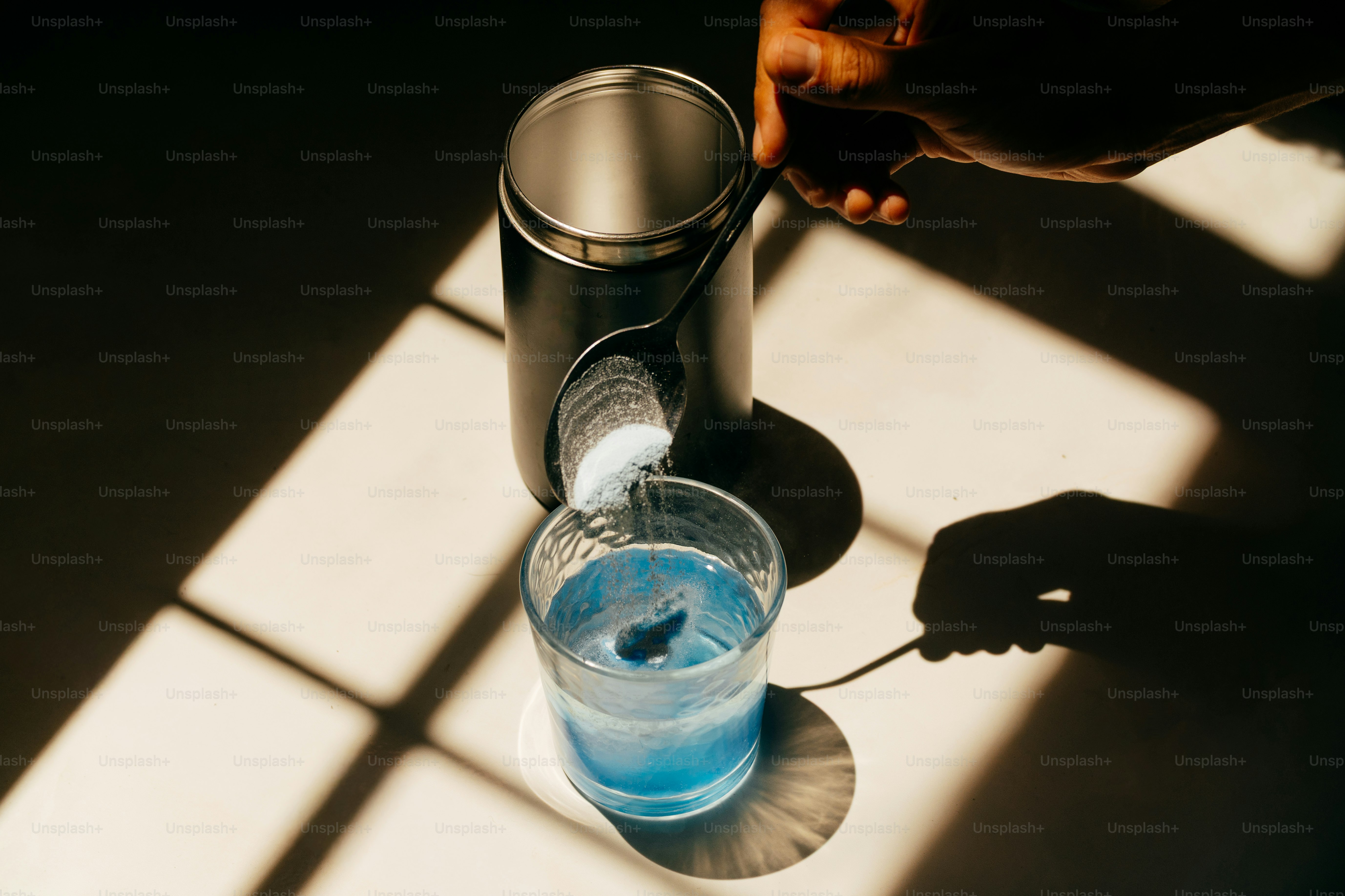 Ajout manuel de poudre dans un liquide bleu dans le verre