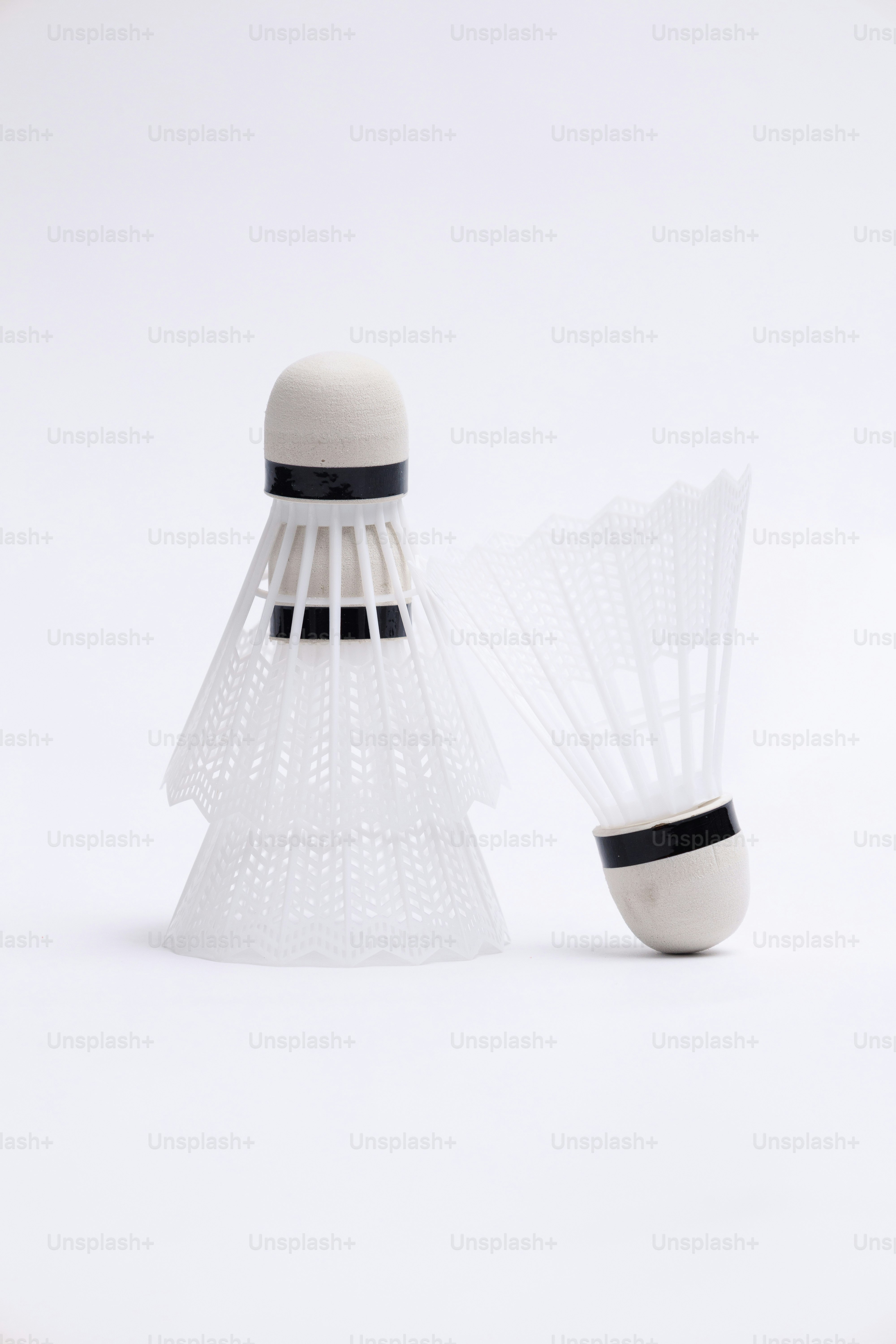Two white badminton shuttlecocks on a white background