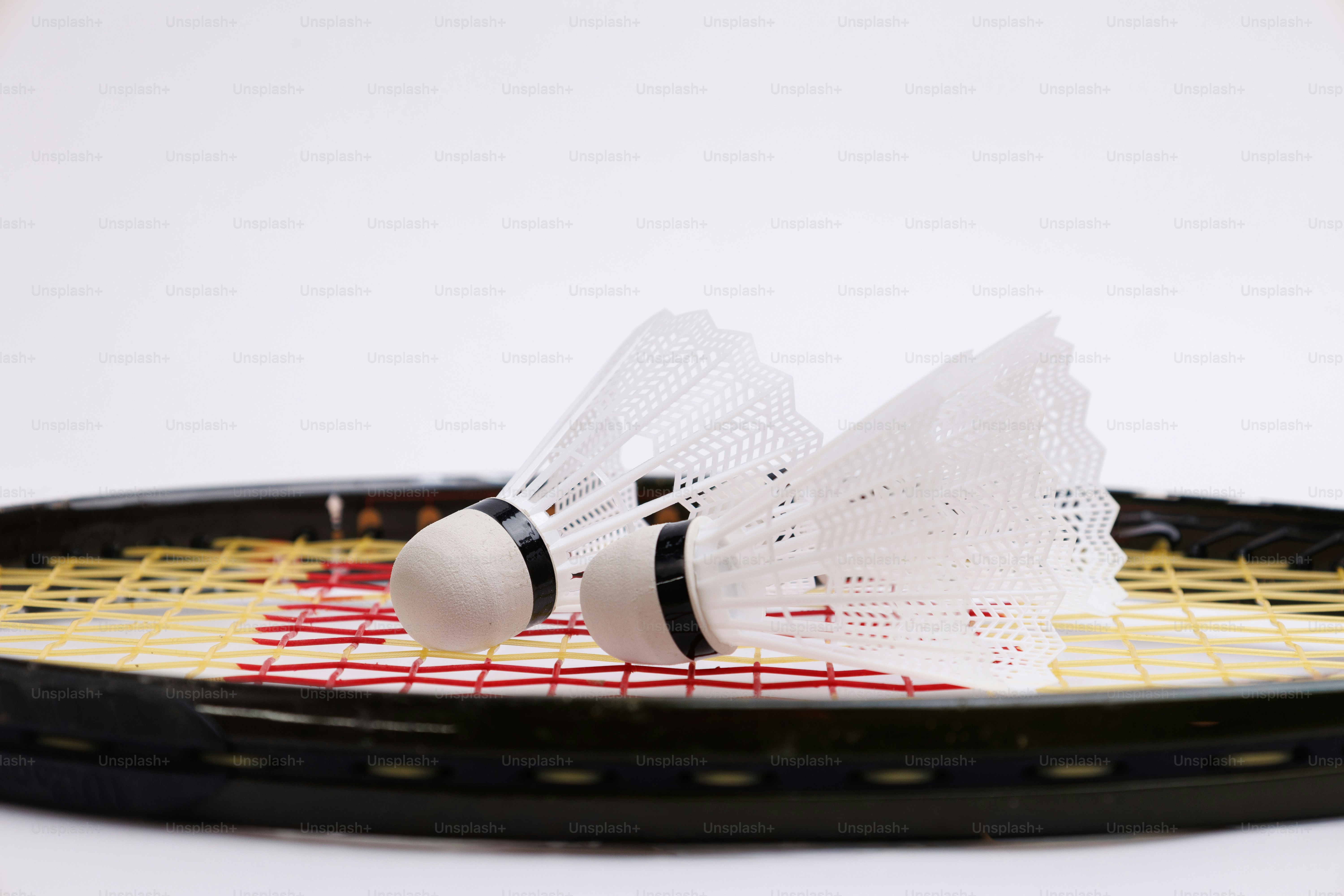 Two shuttlecocks resting on a badminton racket