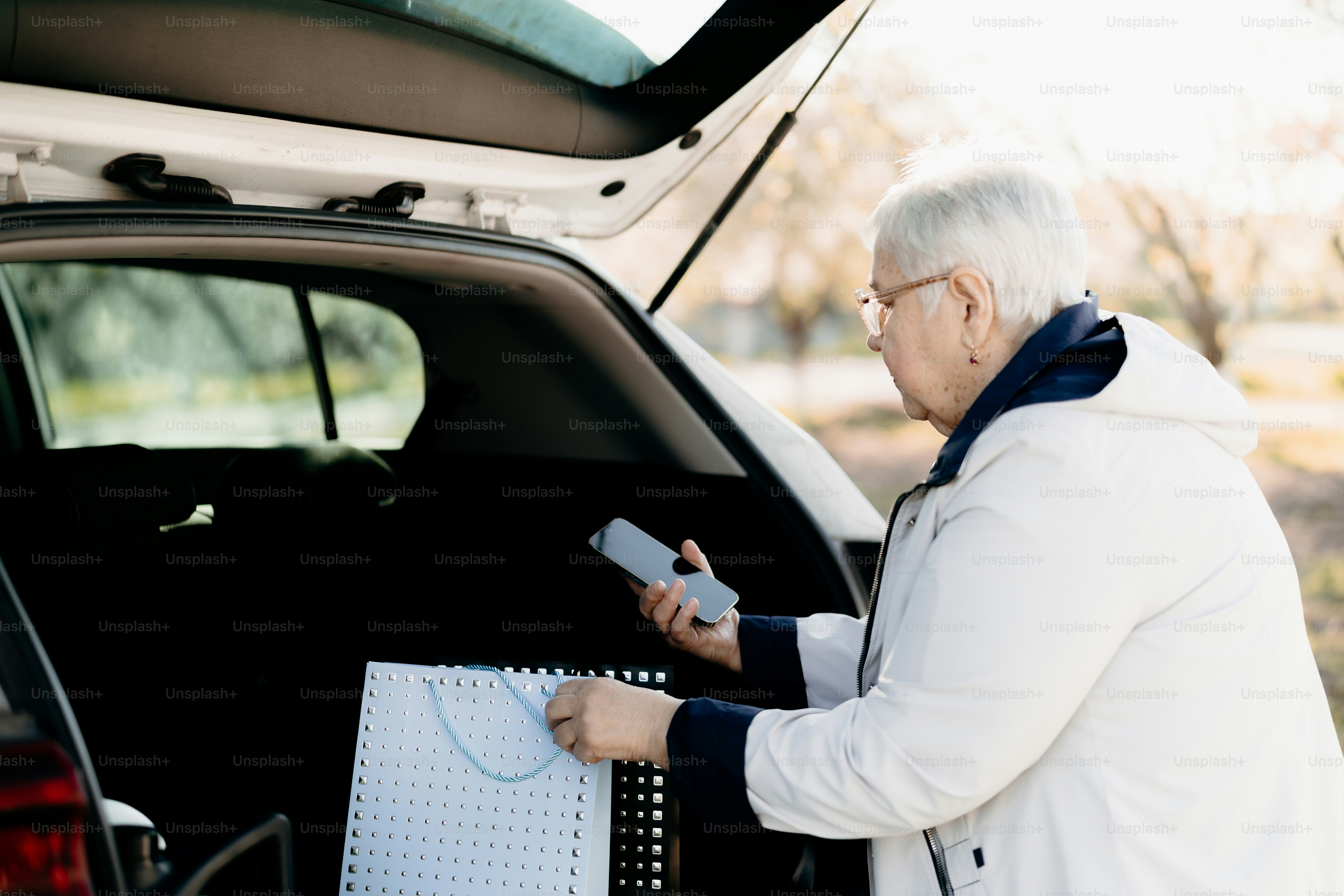 Ältere Frau lädt Lebensmittel in den Kofferraum des Autos