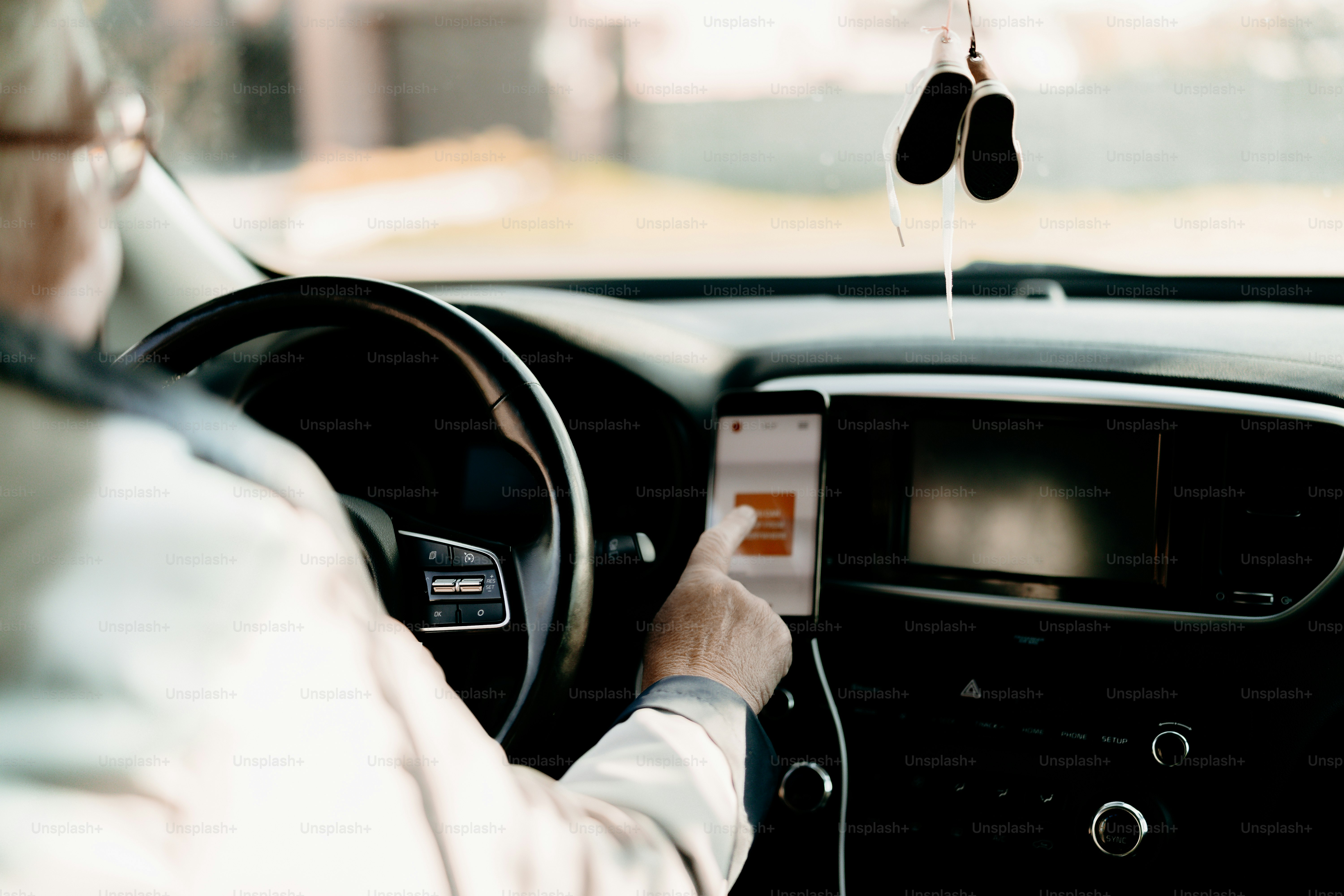 Person, die ein Smartphone benutzt, das am Armaturenbrett des Autos montiert ist