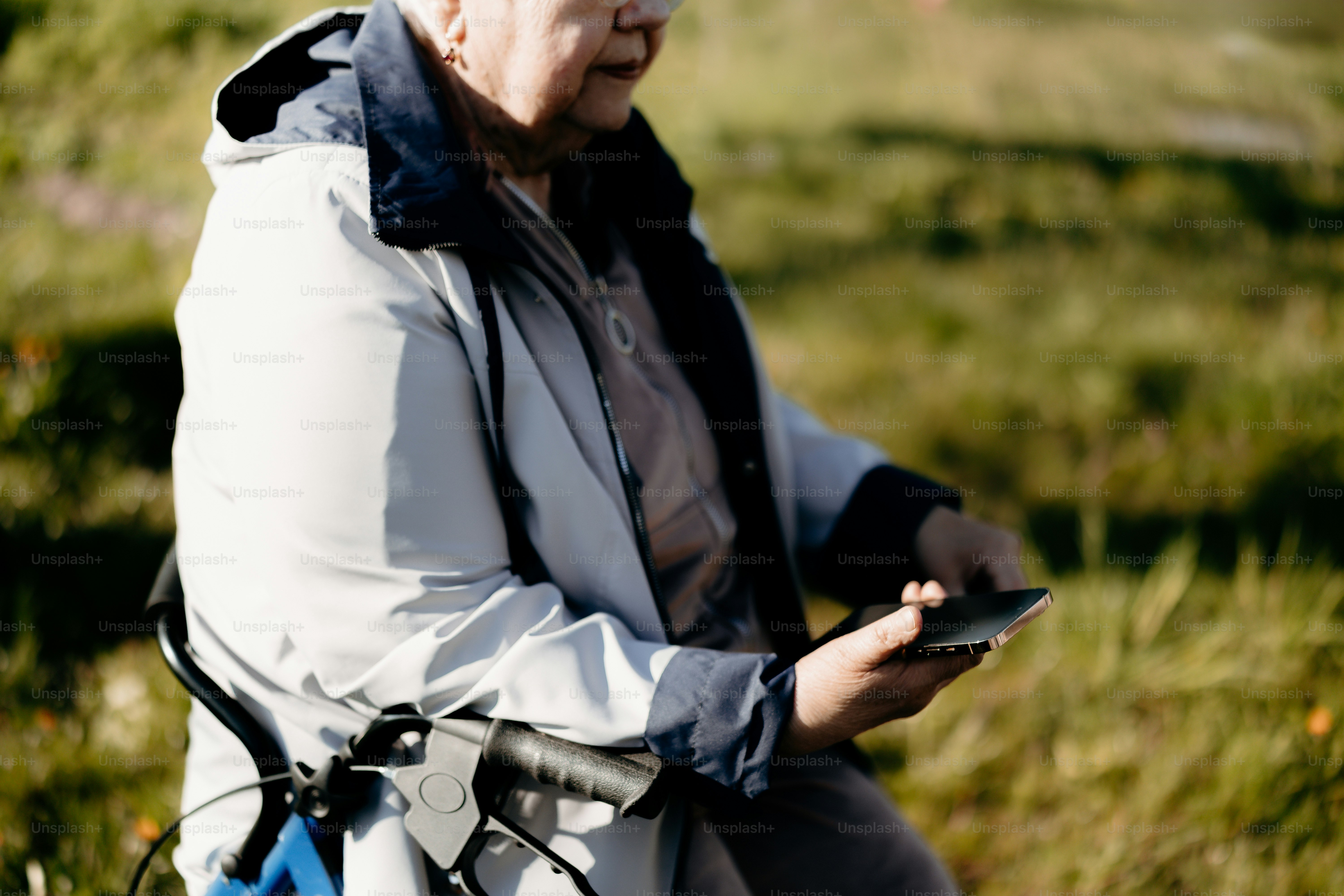 Ältere Person, die ein Smartphone benutzt, während sie mit einem Rollator sitzt.