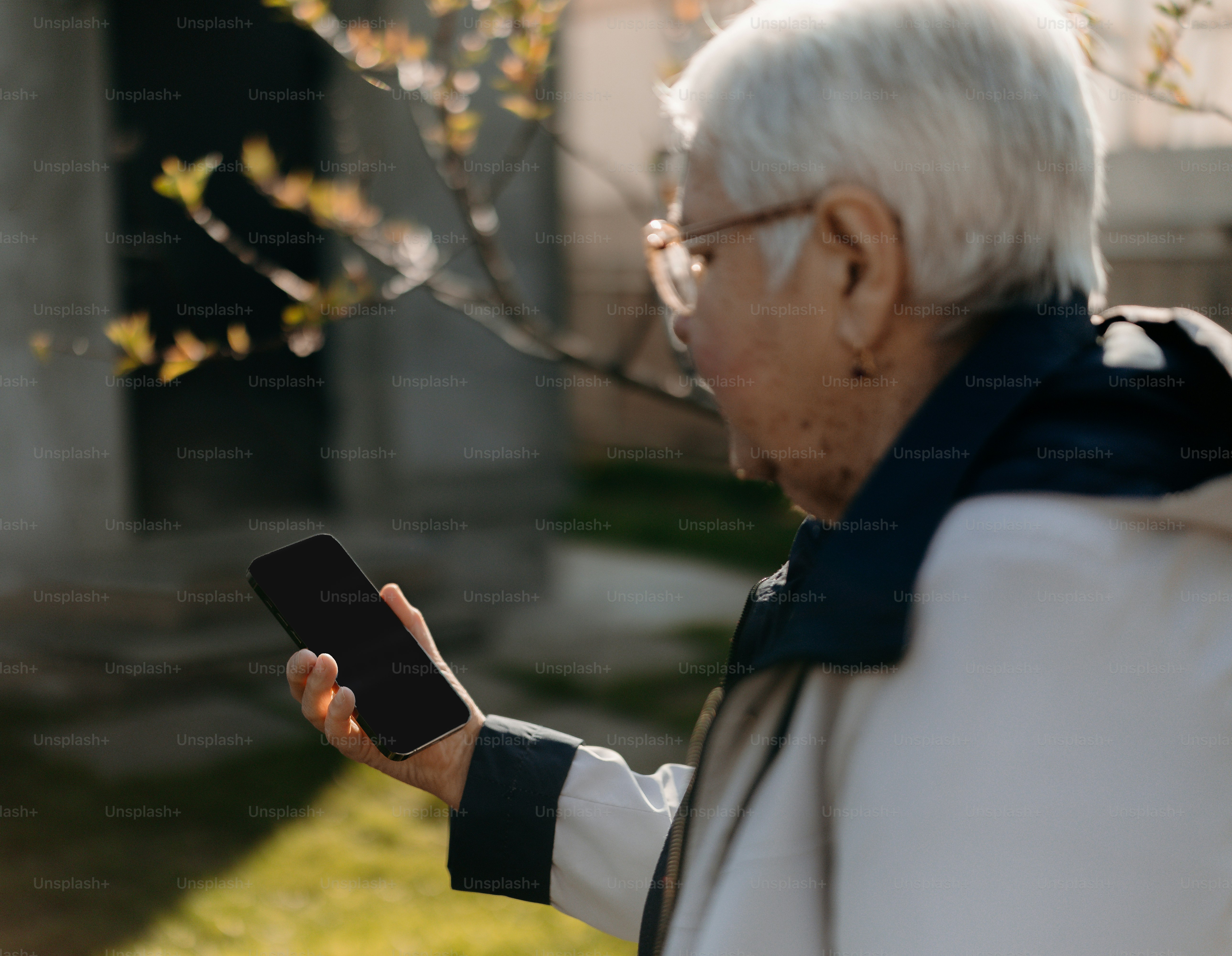 Älterer Mann hält ein Smartphone draußen