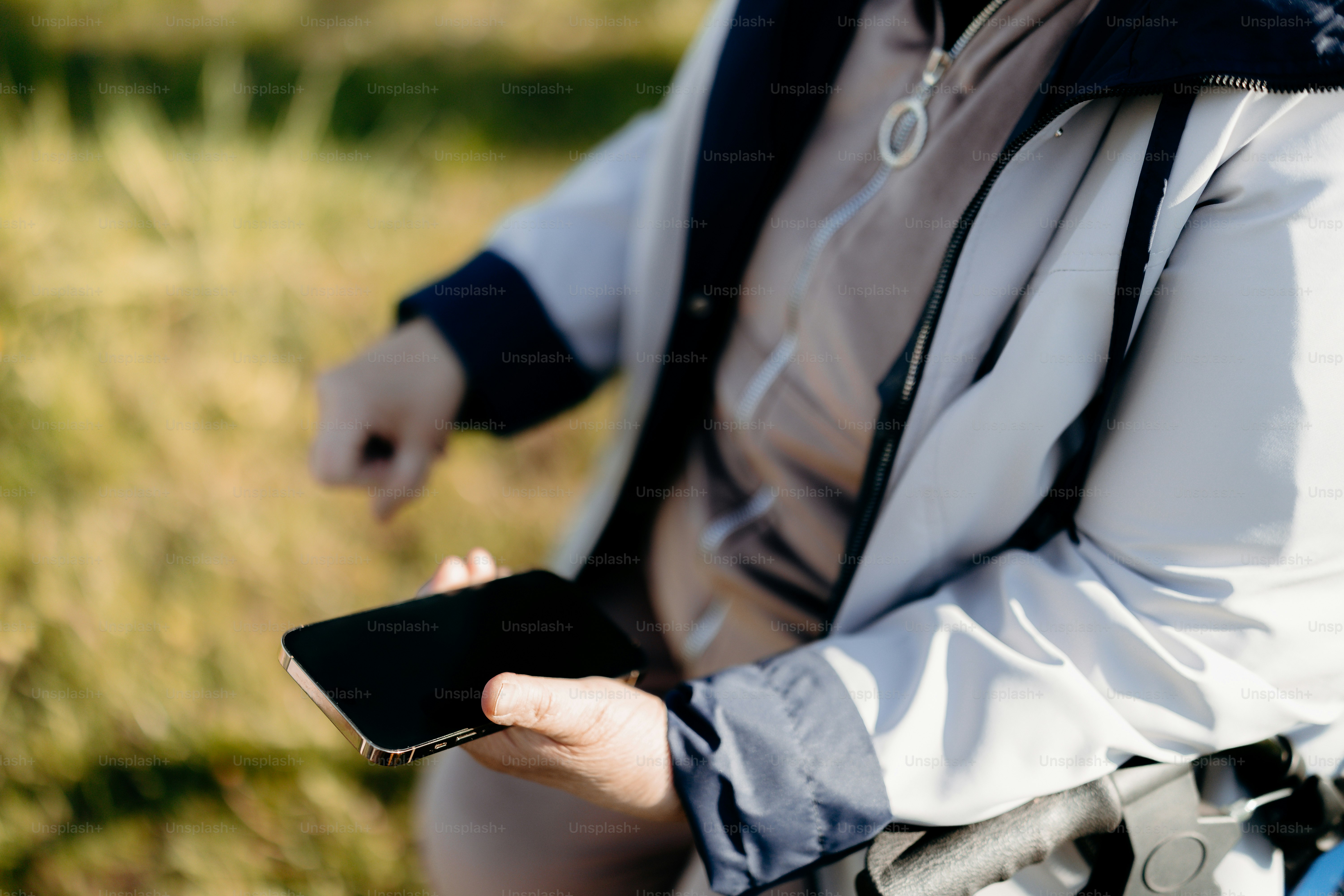 Person, die ein Smartphone draußen mit verschwommenem Hintergrund hält