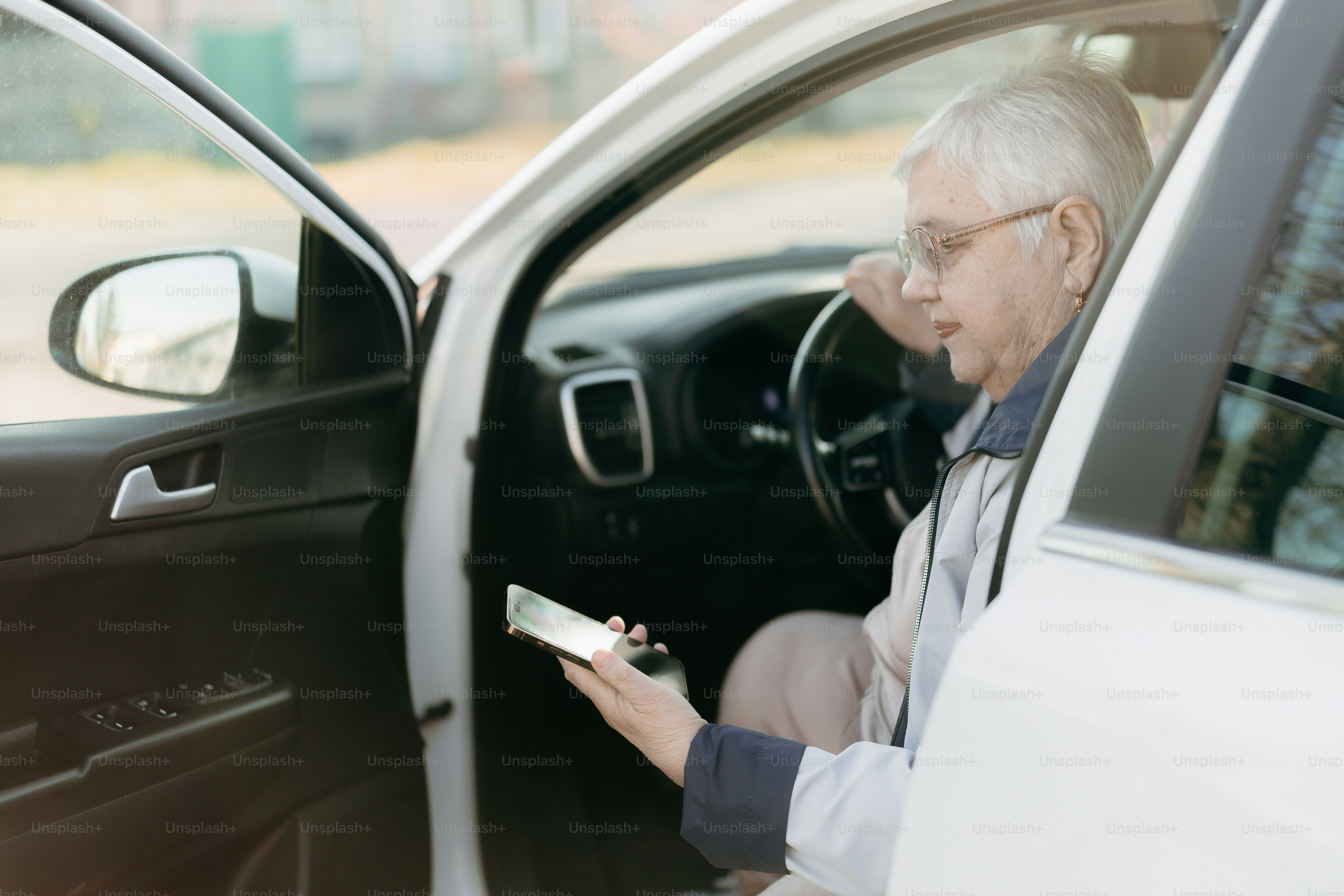 Älterer Mann schaut im Auto auf das Handy